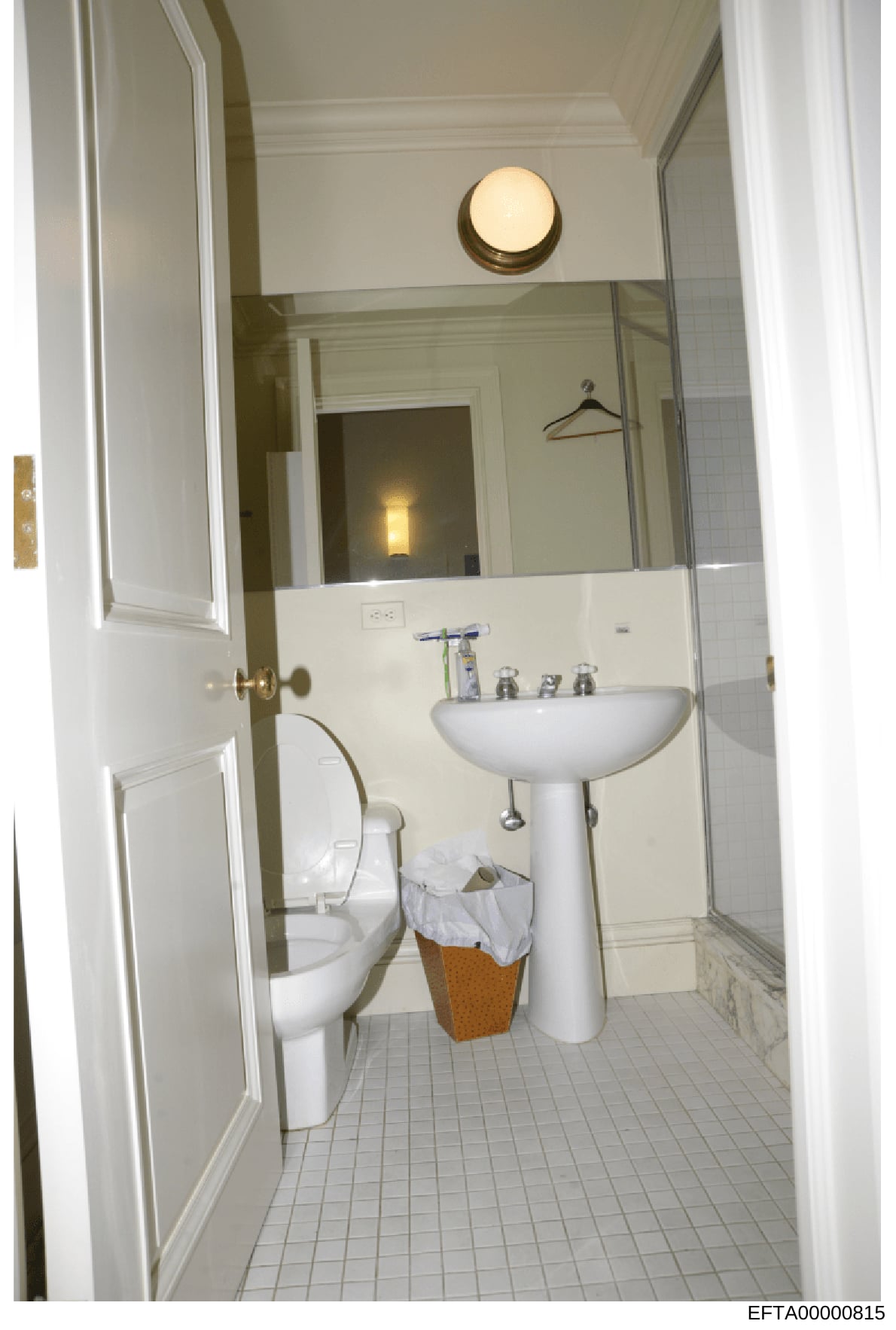 This is a photograph of a bathroom interior, likely from one of Jeffrey Epstein's properties. The image shows a standard residential bathroom with white fixtures and tile flooring, documented as evidence during the investigation. The bathroom appears