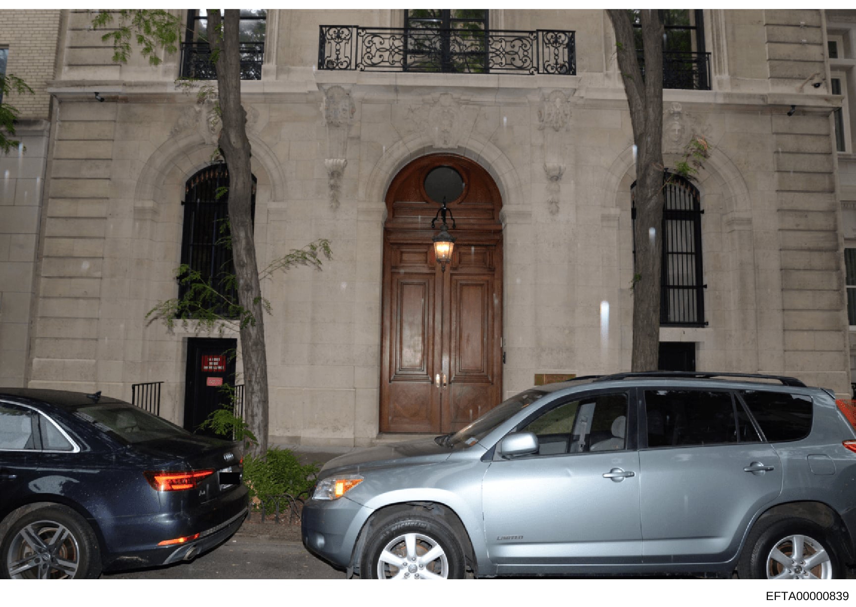 This is a photograph of the facade of an elegant Upper East Side townhouse, likely one of Jeffrey Epstein's New York properties. The image shows the building's exterior architecture, including ornate stonework, a distinctive arched wooden entrance do