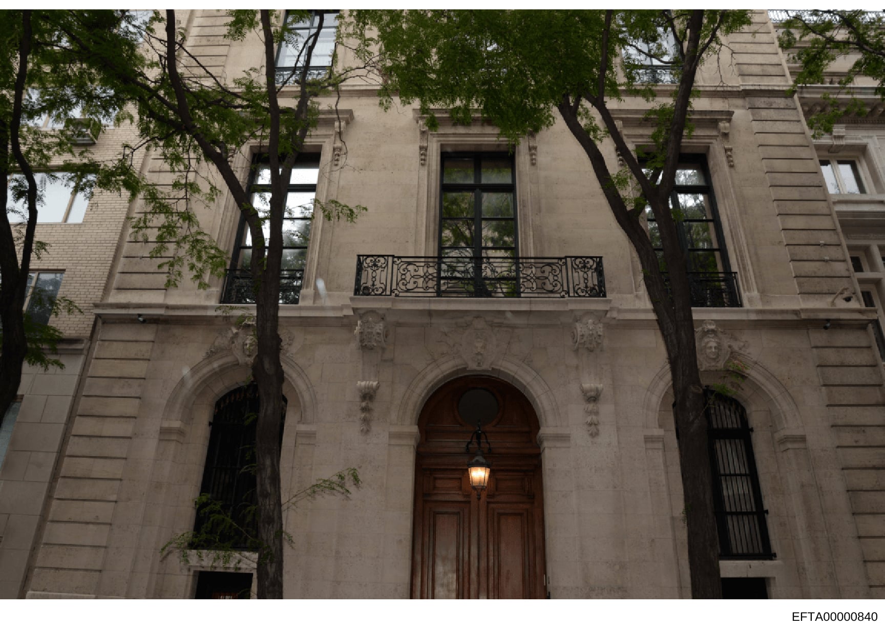 This is a photograph of an elegant Parisian residential building featuring classical Haussmann-style architecture. The facade displays characteristic architectural elements including ornamental stone carvings, wrought-iron balconies, tall windows wit