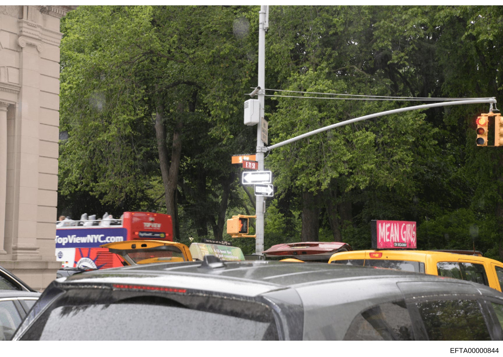 This is a photograph of a New York City street intersection showing yellow taxis, traffic signals, and storefronts. The image appears to be a general street scene photograph, possibly documenting the area around one of Epstein's known properties or a