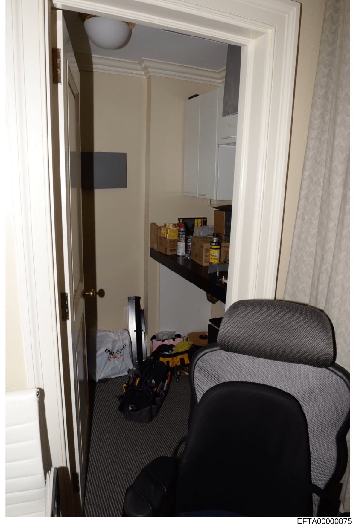 This is an evidence photograph showing an interior room or closet space containing various stored items, shelving units, and personal belongings. The image appears to be taken from a doorway looking into the space, with a gray office chair visible in