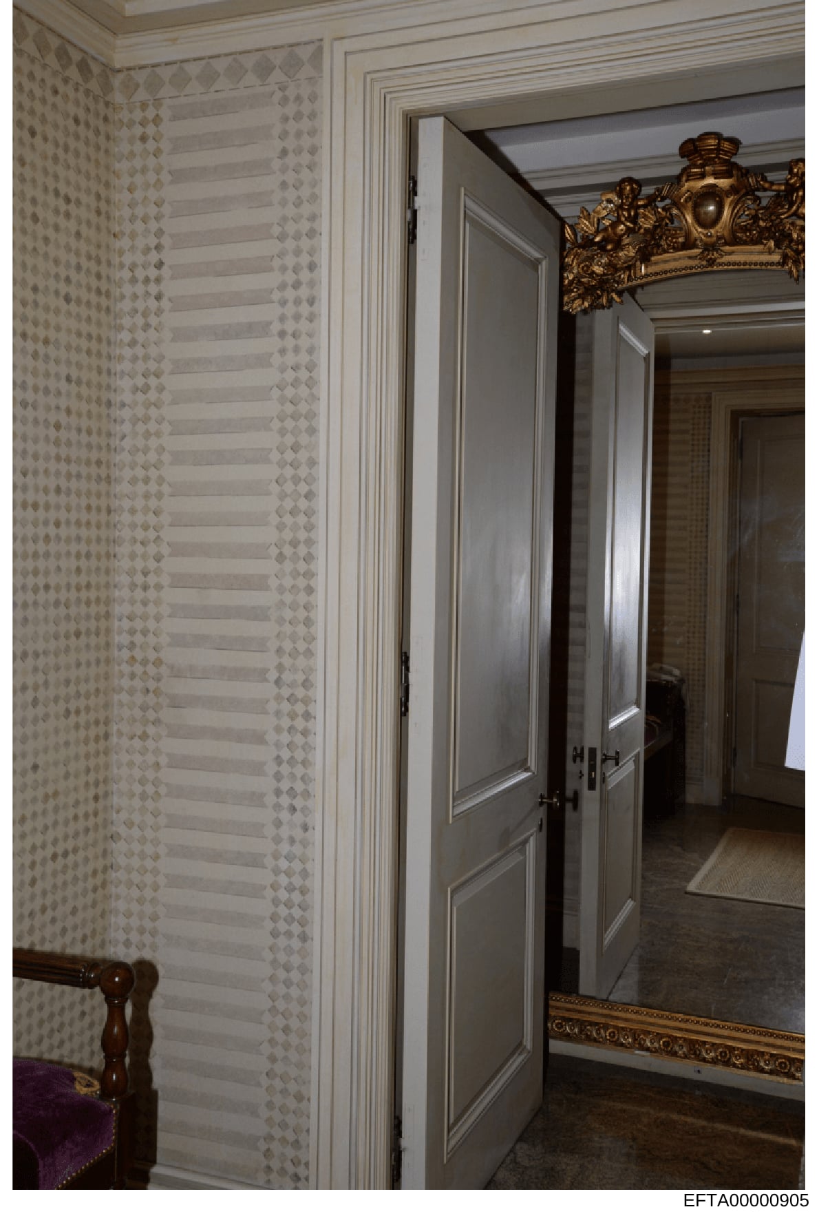 This photograph documents the interior of a high-end residential property, showing a hallway with designer wallpaper, custom paneled doors, and ornate gold-framed mirror. The image appears to be from one of Epstein's properties and serves as evidence