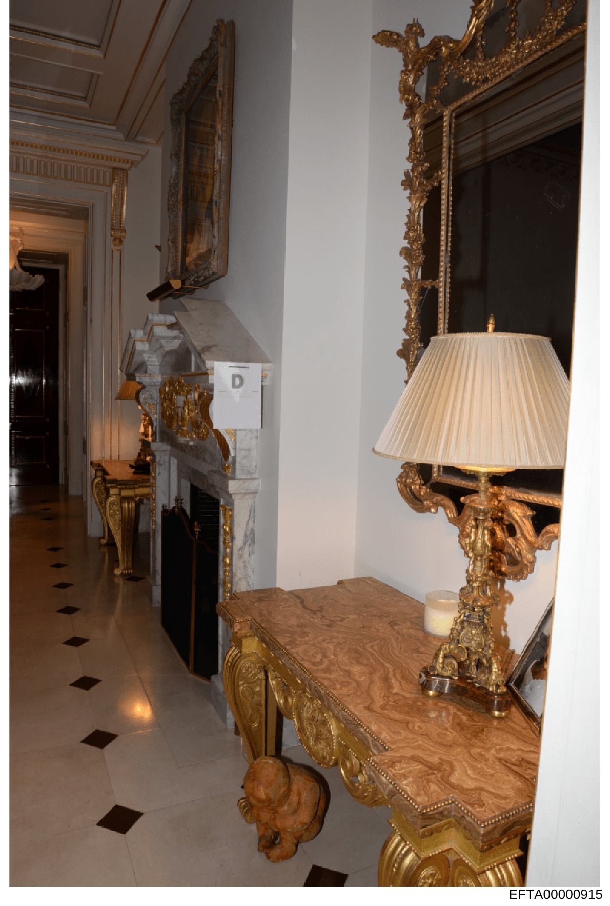 This is a photograph of an ornate interior hallway, likely from one of Jeffrey Epstein's residences, showing luxury furnishings and décor. The image depicts a marble-floored corridor with elaborate gold-leaf mirrors, a wooden console table with ornam