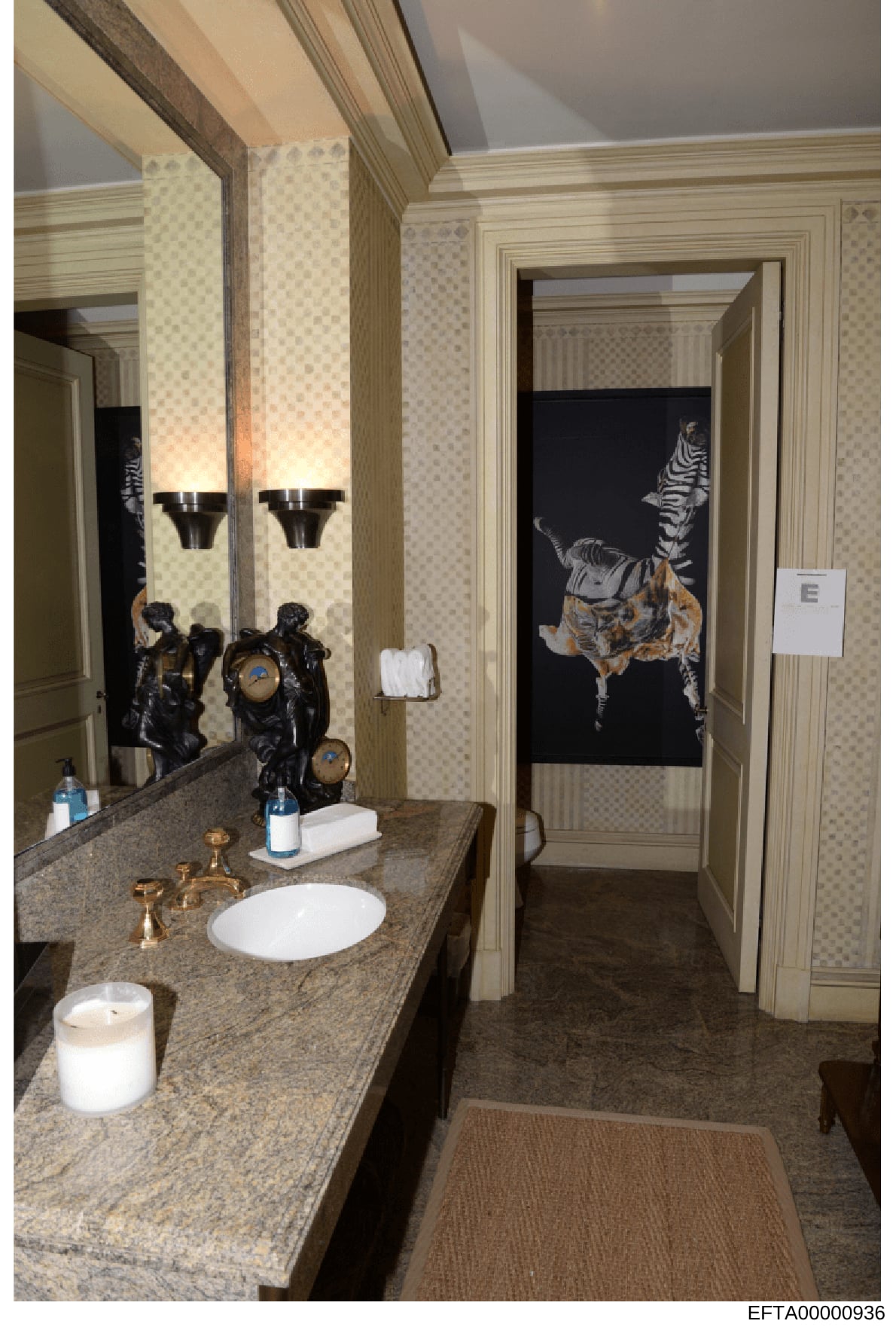 This photograph shows an upscale bathroom interior featuring a marble vanity, designer lighting fixtures, and prominently displayed artwork depicting zebras on a dark background. The image appears to be documentation of property interiors, likely fro