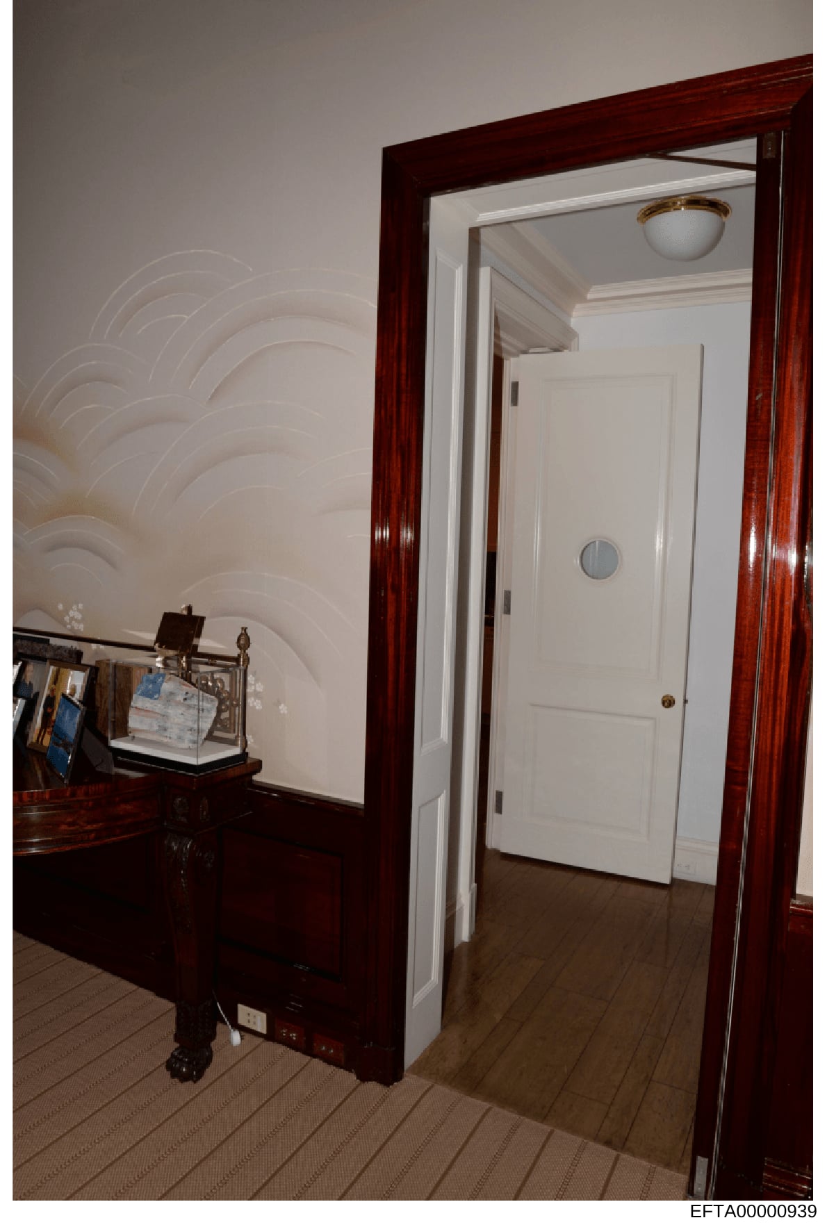 This is an evidence photograph showing the interior of a residential space, featuring a room with dark wood-trimmed doorway and furnishings. The image captures decorative details including a piano or large dark wooden furniture piece on the left, wal
