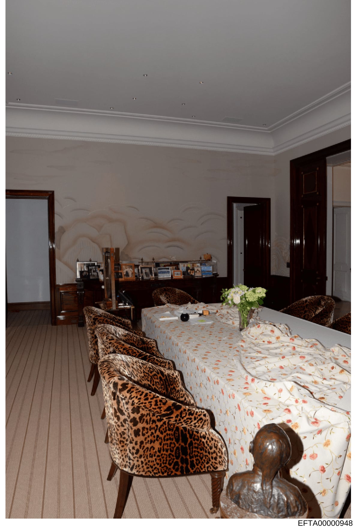 This is a photograph of an upscale bedroom interior, showing high-end furnishings including leopard-print chairs, a bed with decorative bedding, dark wood furniture, and framed photographs on a dresser. The room features professional interior design 
