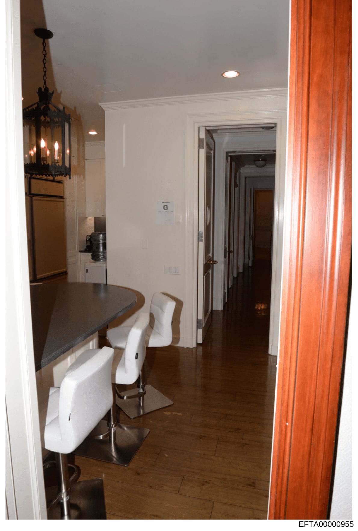 This is a color photograph showing the interior of a residential kitchen and adjoining hallway. The image documents the layout, furnishings, and design elements of what appears to be a luxury residential property, featuring modern kitchen fixtures, d
