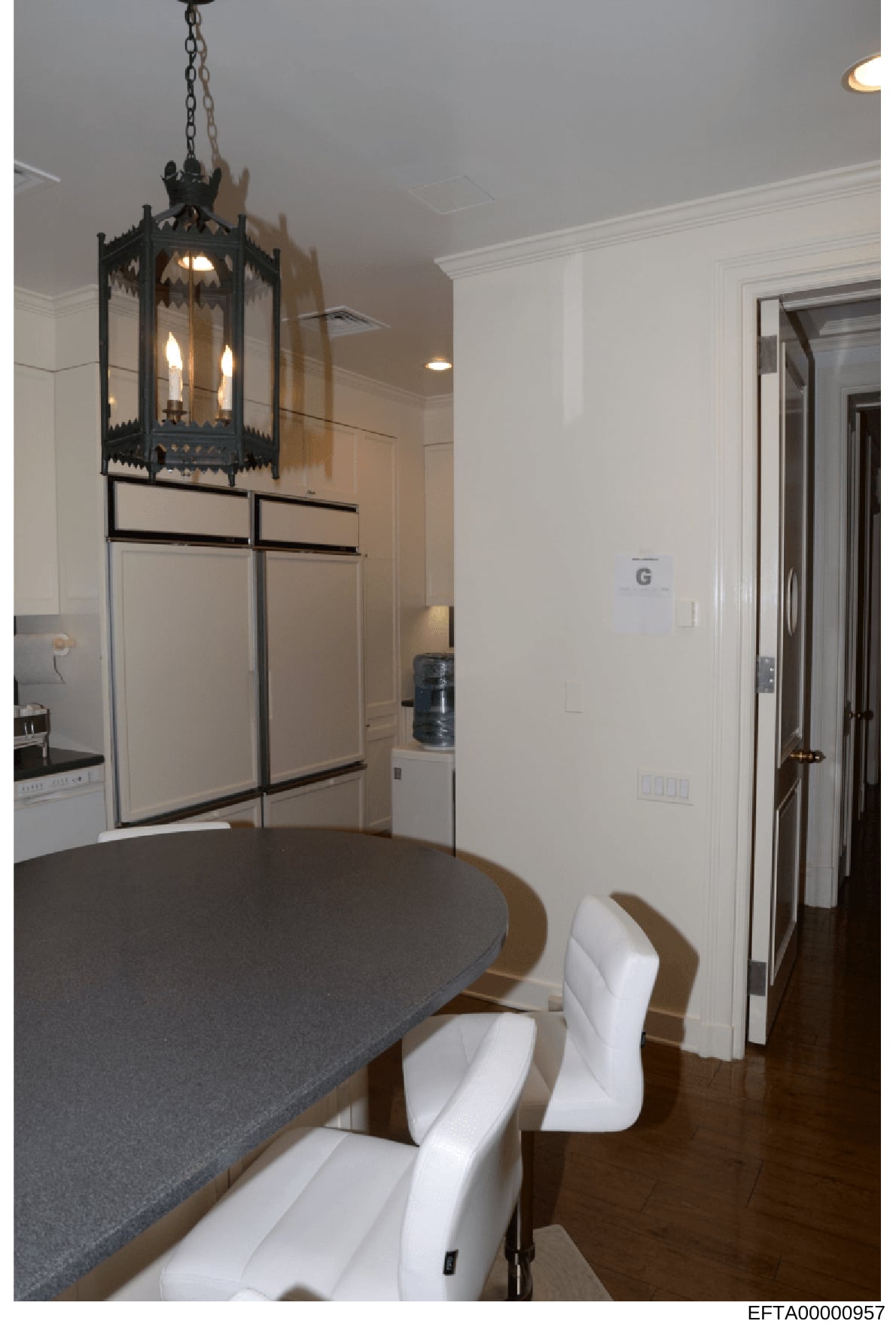 This is a photograph of a contemporary kitchen interior featuring custom white cabinetry, a decorative black pendant light fixture, and dark countertops. The image shows professional renovation or property documentation, typical of evidence photos co