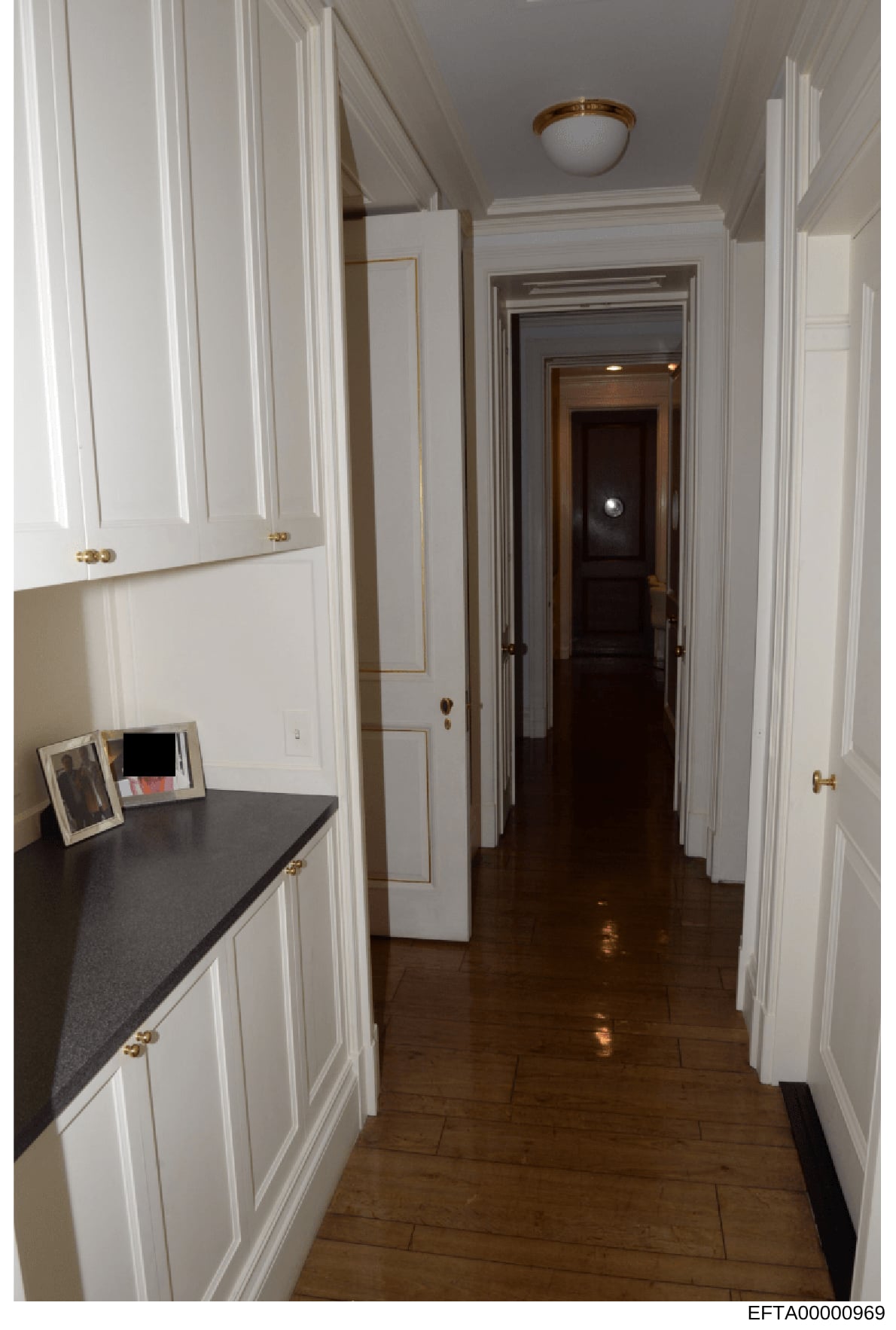 This is a photograph of an elegant hallway in what appears to be one of Jeffrey Epstein's residences, showing white paneled cabinetry, dark wood flooring, brass fixtures, and multiple doorways. The image documents the interior architectural design an