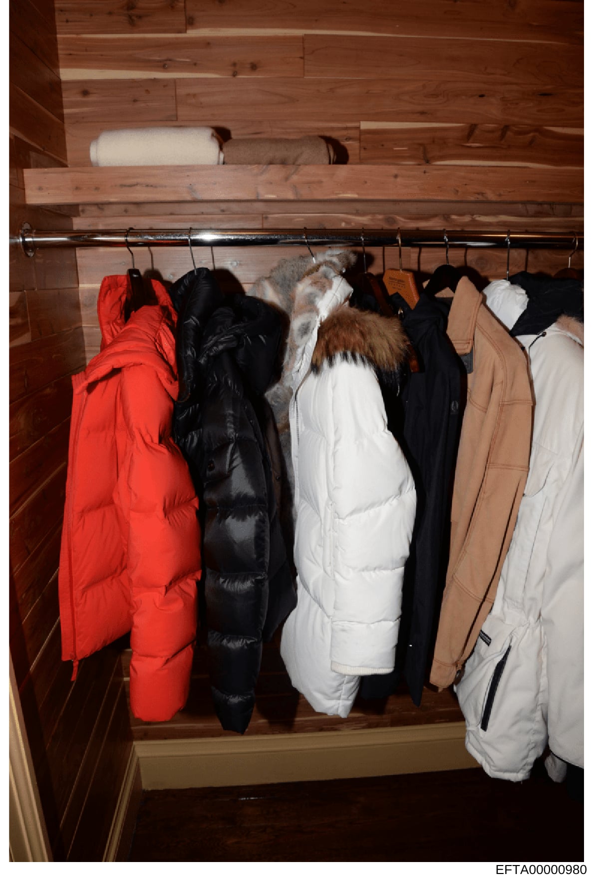 This is an evidence photograph showing the interior of a wooden-paneled closet containing multiple winter outerwear items hanging on a rod. The photo appears to be documentation of a residential space, likely taken during the investigation into Jeffr