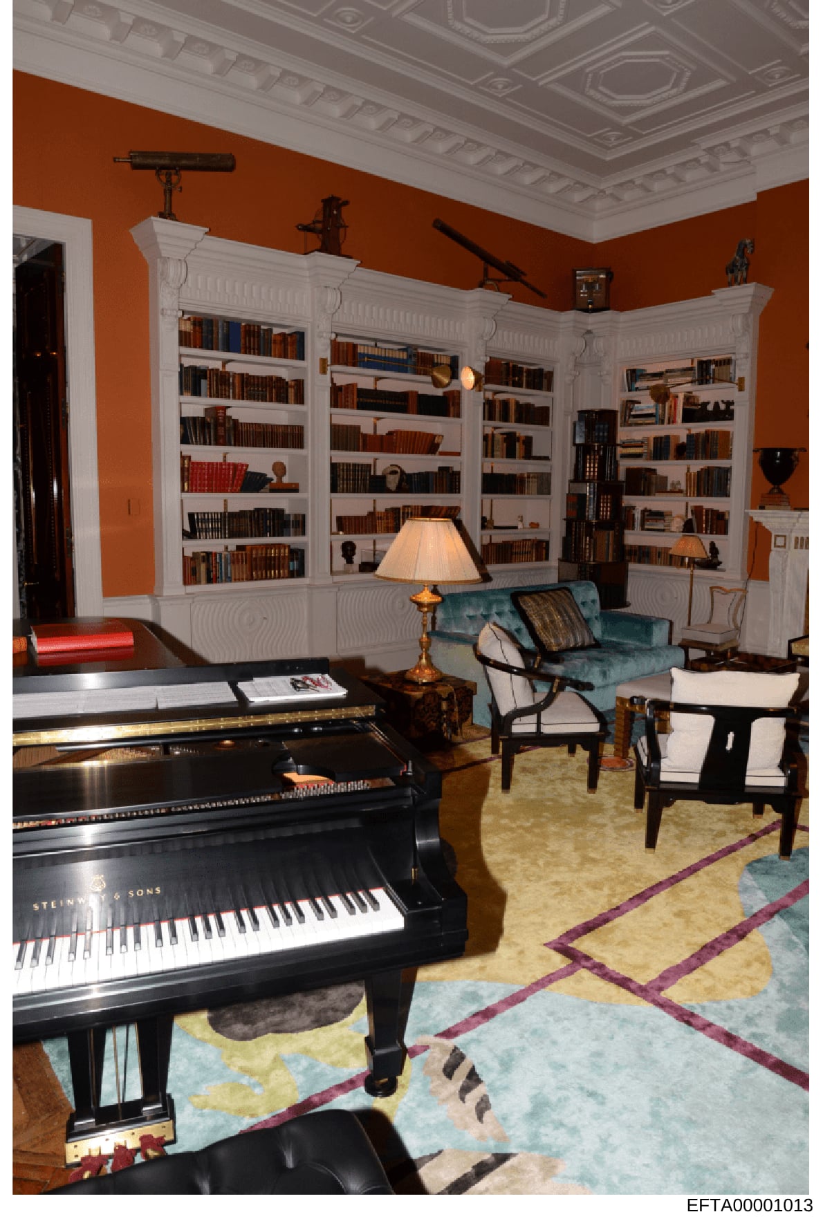 This is a photograph of a luxurious residential interior space, likely from one of Epstein's properties, featuring a grand piano, extensive built-in bookshelves, and high-end furnishings. The room displays significant wealth through its architectural