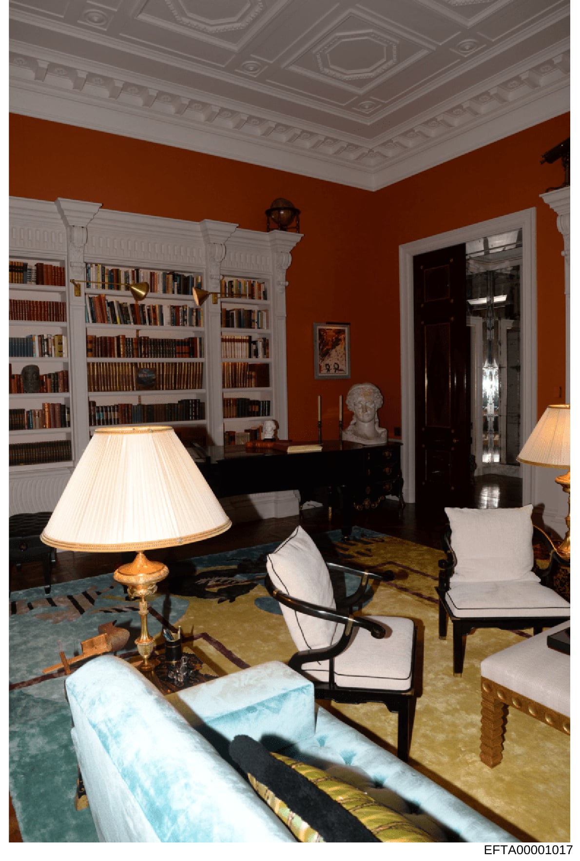 This is an interior photograph documenting a luxuriously appointed library or study room featuring white built-in bookshelves, rust-colored walls, ornate plasterwork ceiling, and period furniture. The image appears to be evidence documentation of pro