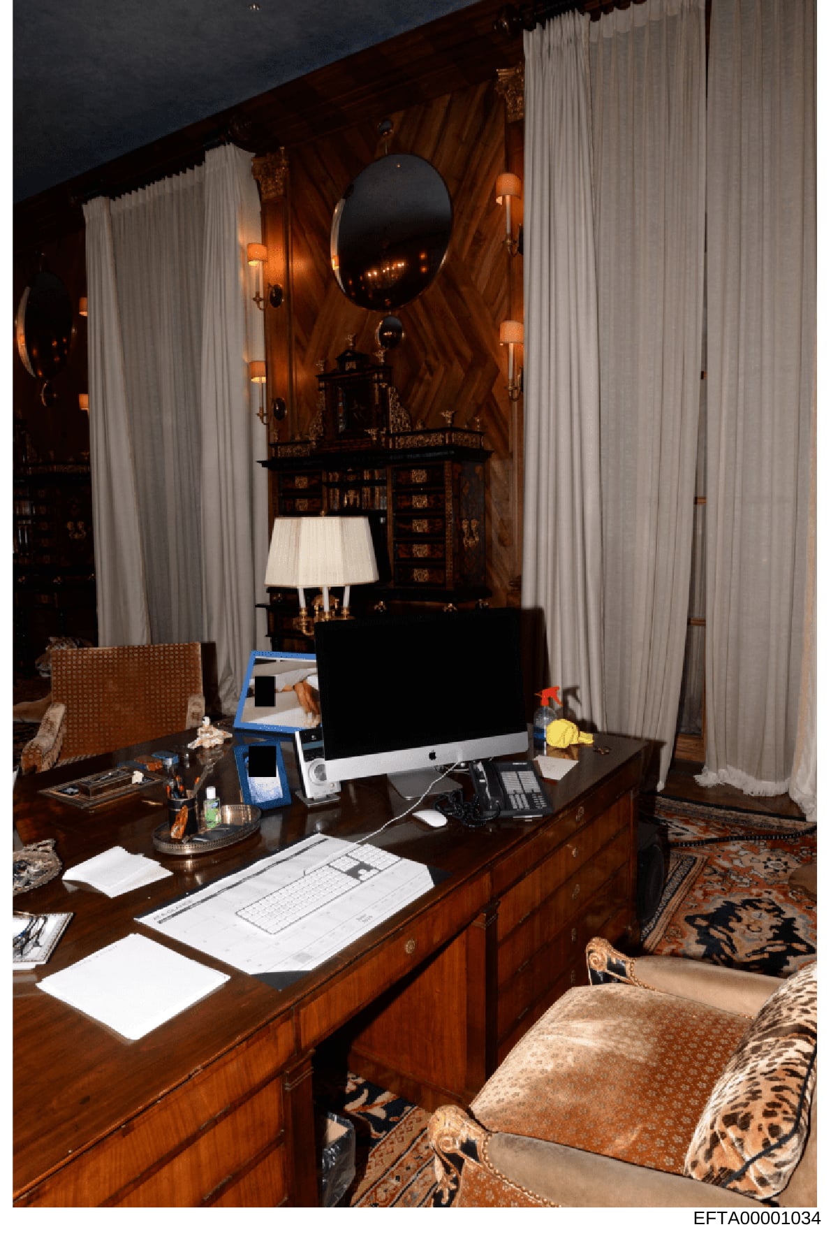This photograph shows a luxuriously appointed interior room featuring a wooden desk with modern computer equipment, ornate furnishings, and detailed décor. The room displays high-end styling with rich wood paneling, heavy curtains, decorative mirrors