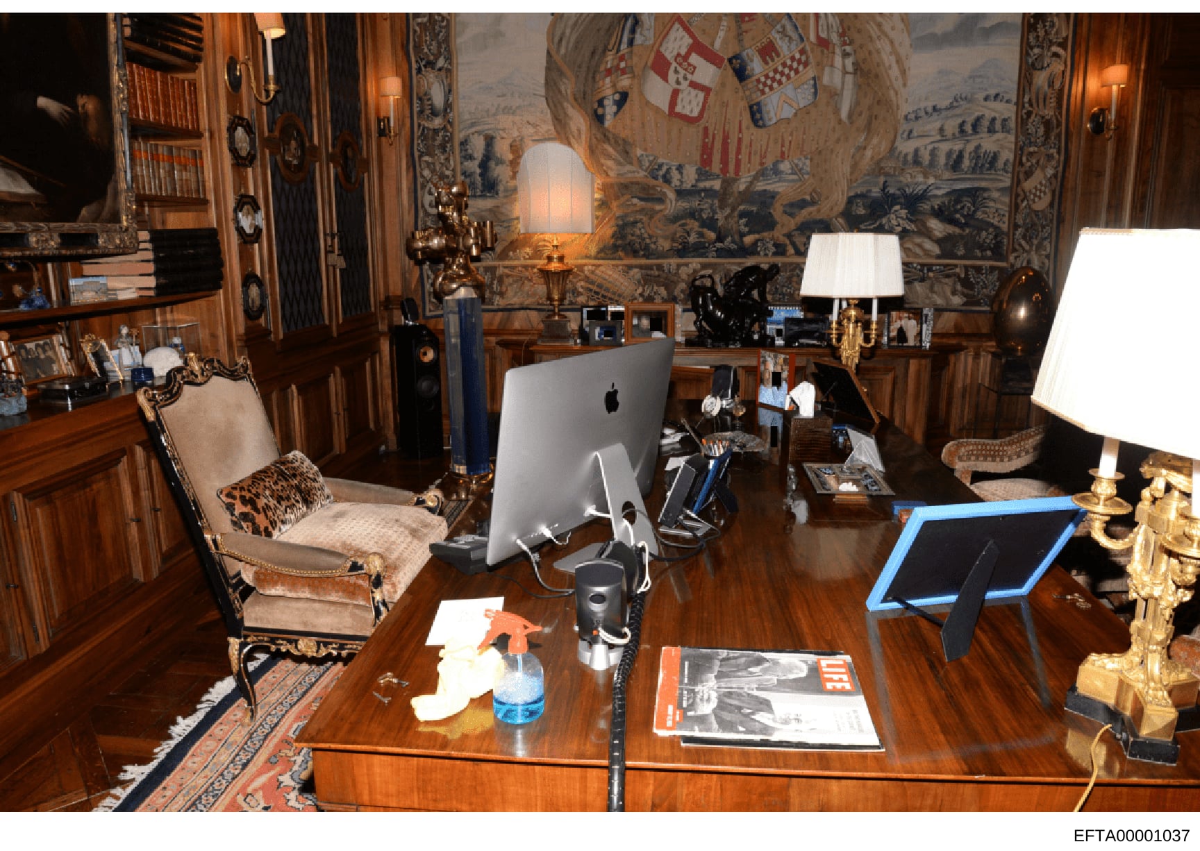 This photograph documents the interior of an opulently furnished office space, likely belonging to Jeffrey Epstein, showing expensive wood paneling, fine art including a large tapestry, antique furniture, and modern computer equipment. The room refle