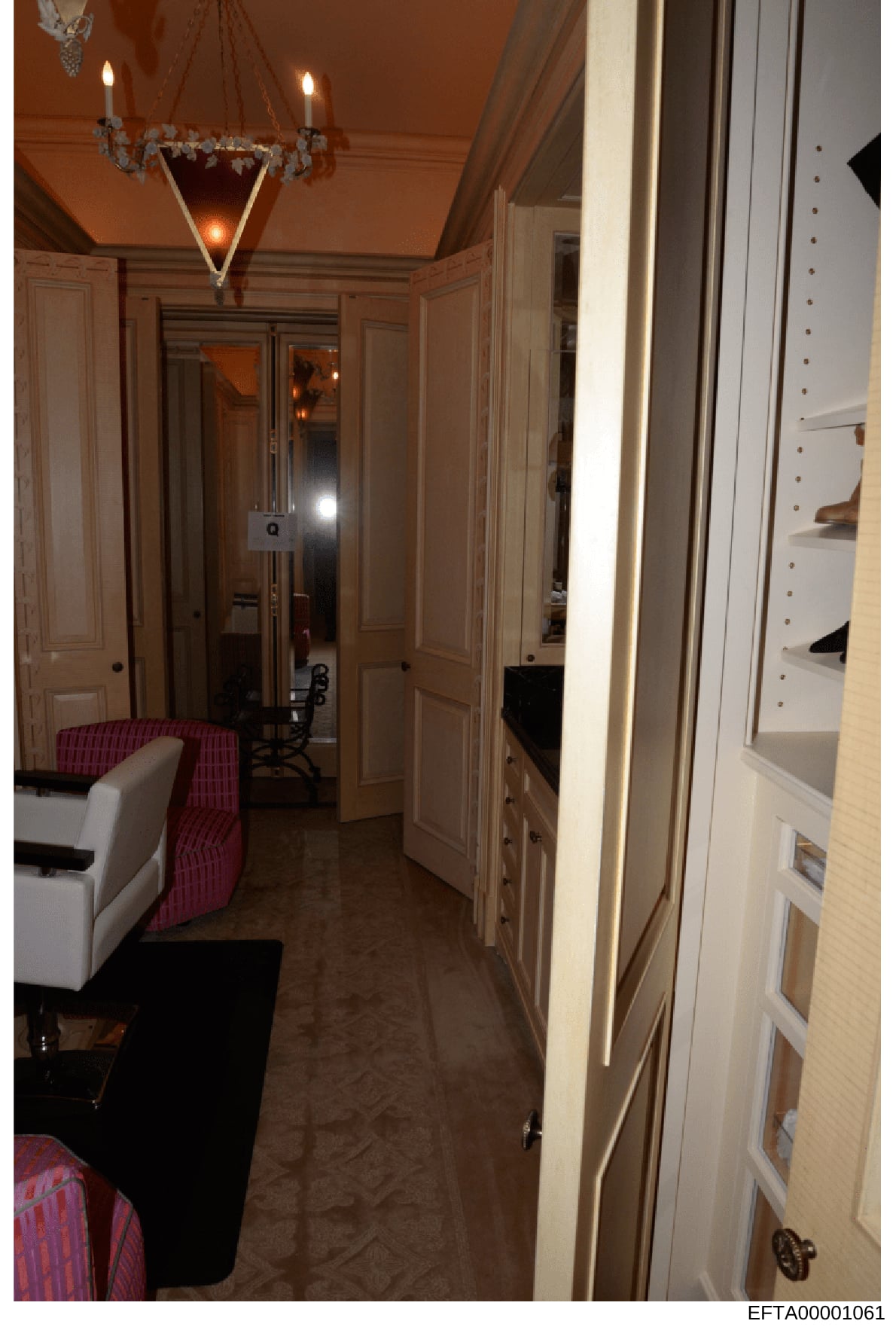 This photograph shows an elegantly decorated interior space featuring a dressing room or closet area with cream-colored paneled doors, ornate chandelier lighting, and built-in cabinetry. The room exhibits high-end furnishings including a white uphols