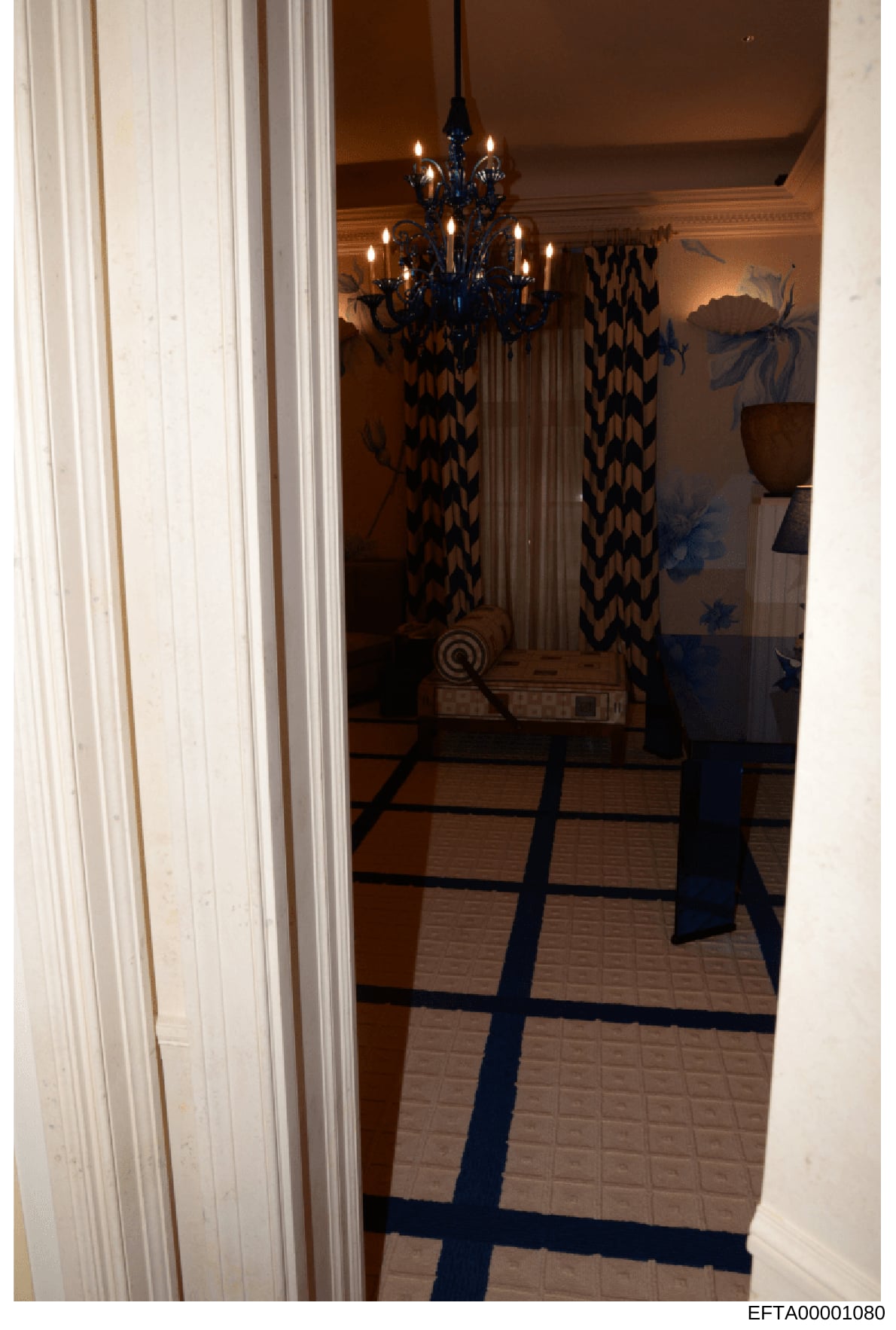 This is an evidence photo from an Epstein-related property showing an interior hallway or entryway of a luxurious residence. The image depicts elegant decor including a decorative chandelier, patterned curtains, and ornate flooring, consistent with d