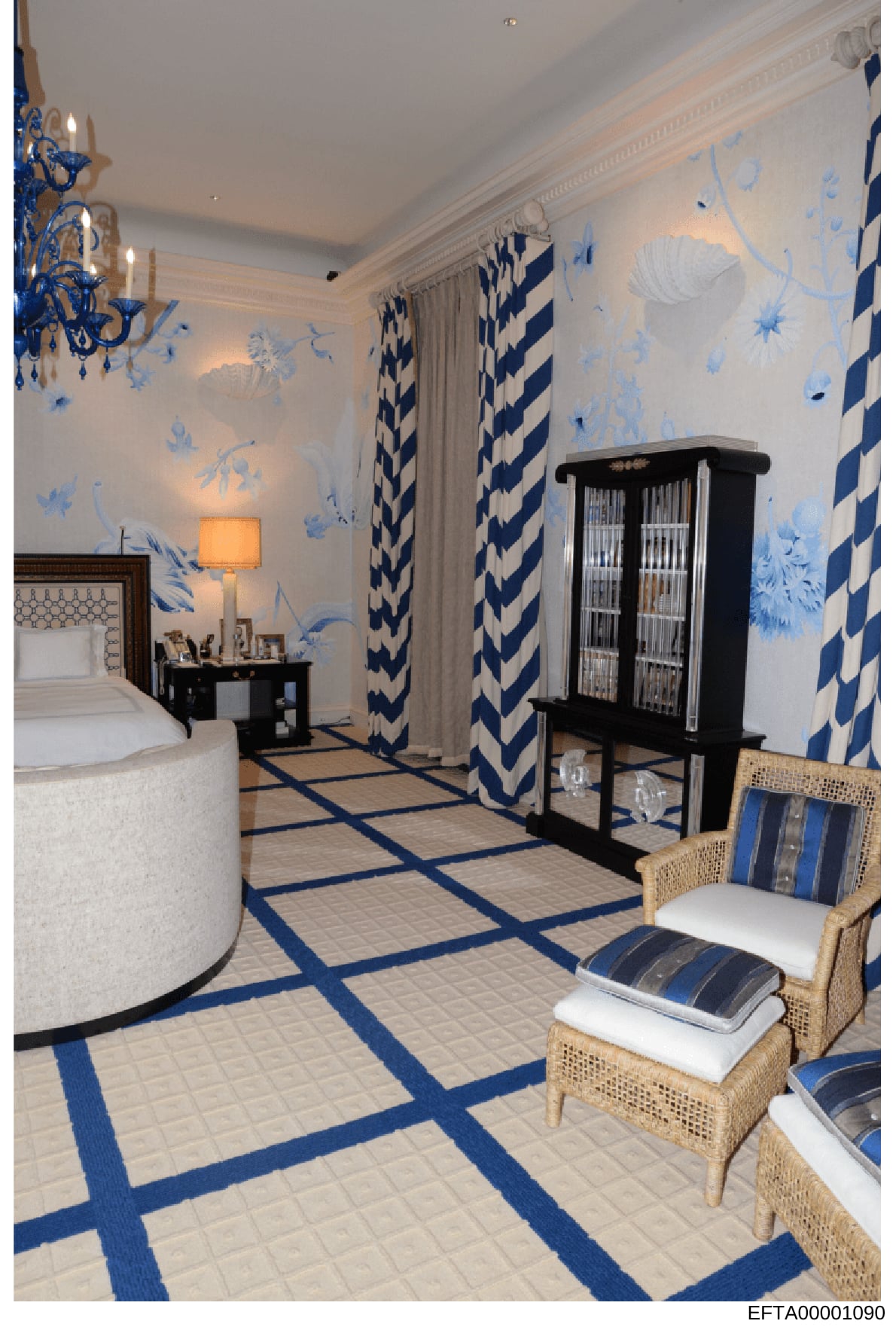 This is a photograph of an elegantly decorated bedroom featuring a sophisticated color scheme of blue, white, and cream. The room displays high-end interior design with custom wallpaper, quality furnishings, and professional styling. The image appear