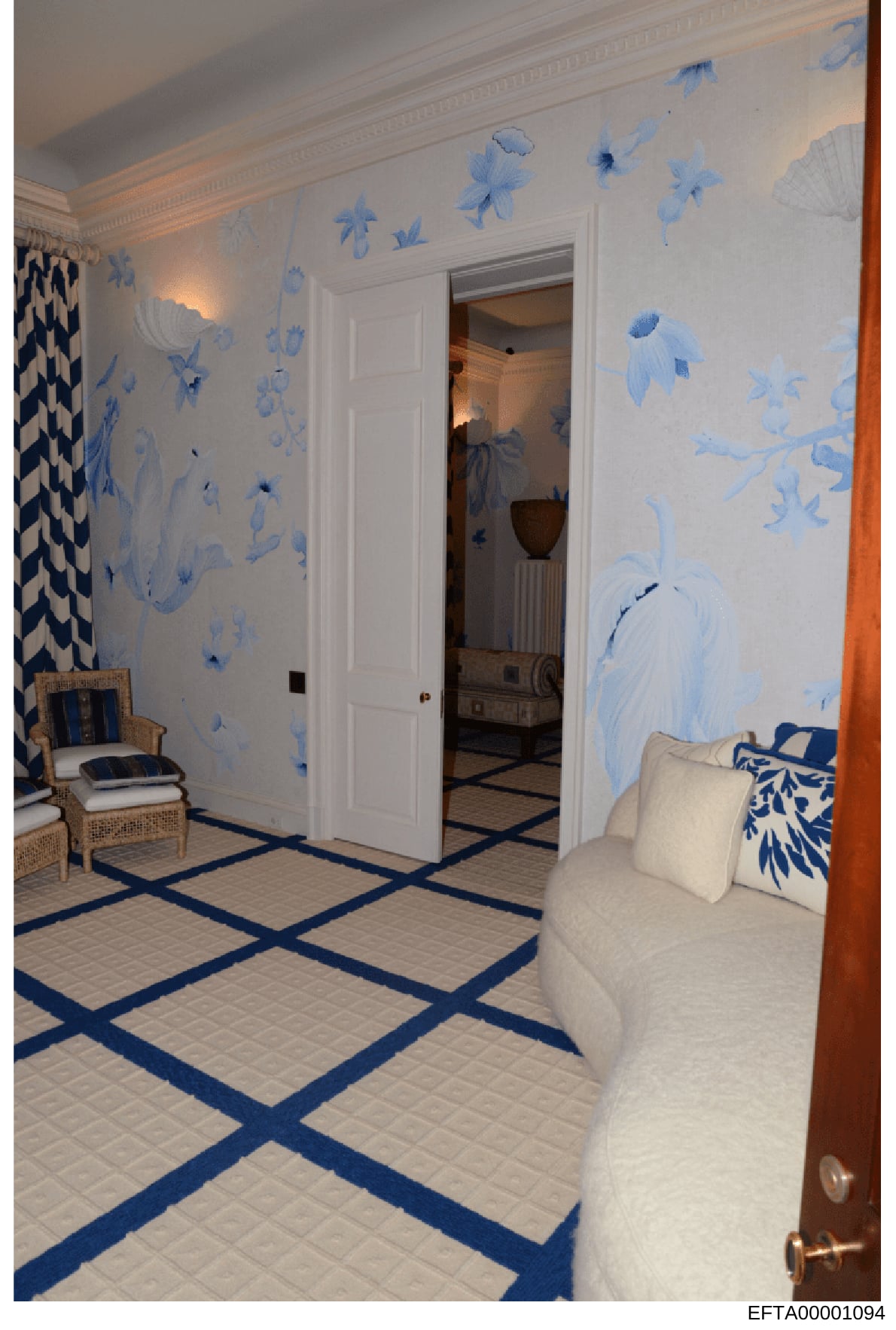 This photograph shows an elegantly decorated interior room featuring blue and white botanical wallpaper, white crown molding, and geometric patterned flooring with navy blue accents. The room contains upholstered furniture and is part of the evidence