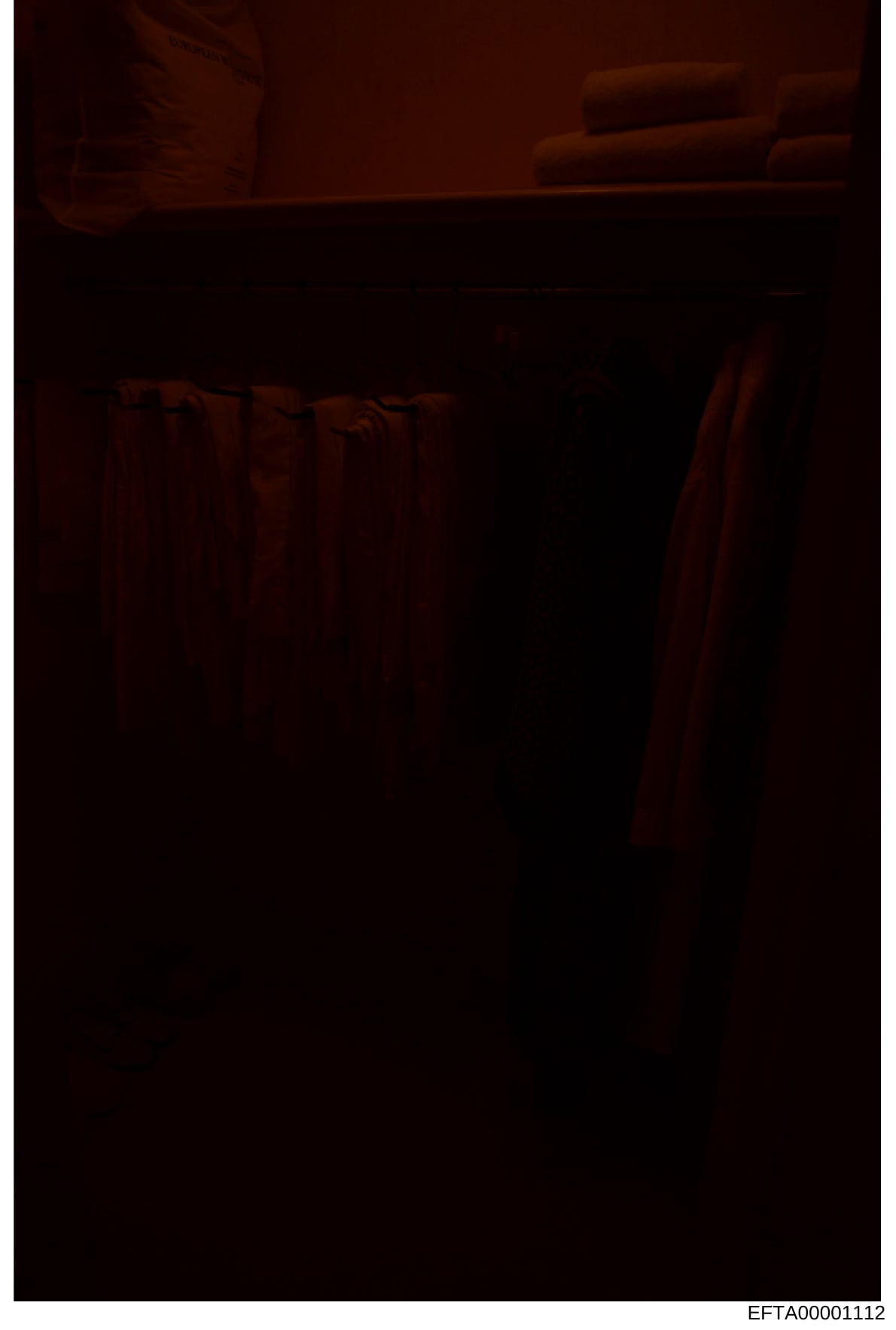 This is a photograph of an interior room showing furniture in warm lighting conditions. The image is severely underexposed and difficult to interpret clearly, but appears to show a residential space with what looks like a bed frame and other furnishi