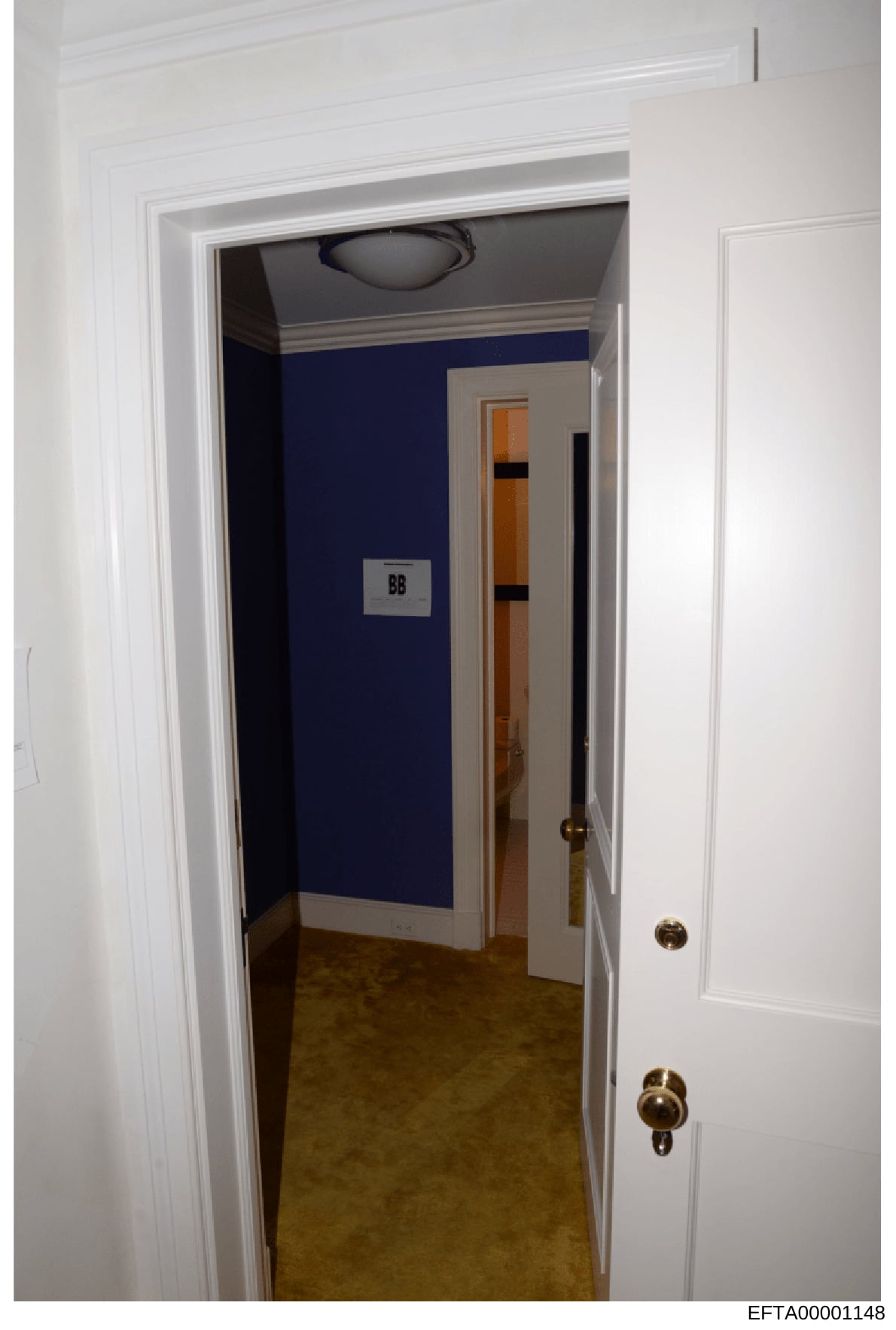 This is a photograph of an interior hallway in what appears to be a residential or commercial property. The hallway features white trim, dark blue wall paneling, and a room marked with 'BB' visible through the open doorway. The image appears to be pa
