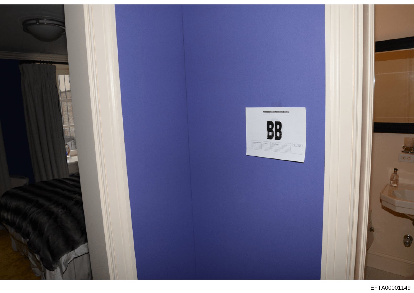 This is an evidence photograph from an Epstein property showing an interior room with distinctive blue walls. A white evidence marker labeled 'BB' is attached to the wall, indicating this photo was taken as part of the official investigation document