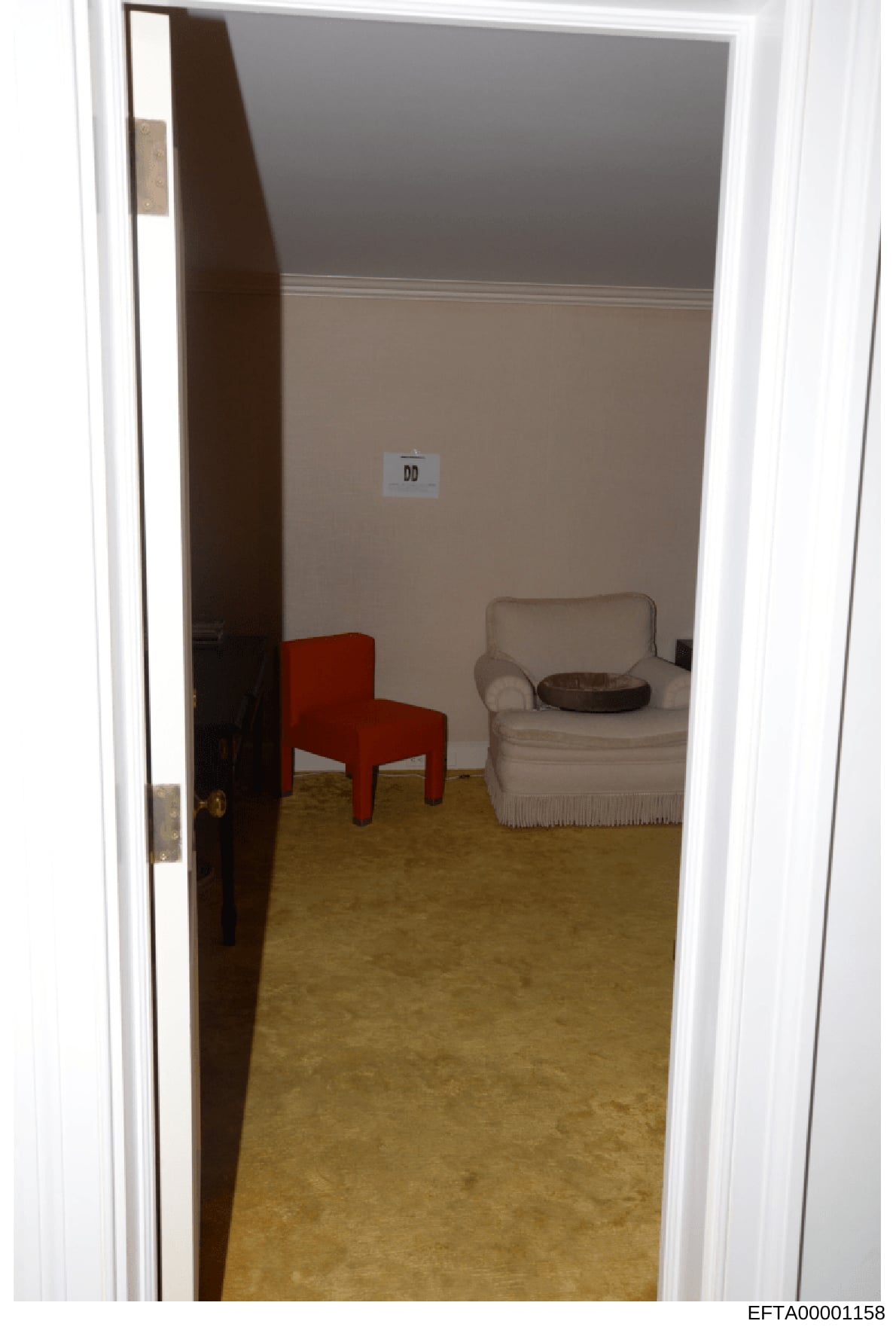 This is an evidence photograph showing the interior of a room with two-tone painted walls (gray upper, beige lower), a tan/cream colored chair with fringe, a red modern chair, and a brown object on the chair. A small evidence marker labeled 'DD' is v