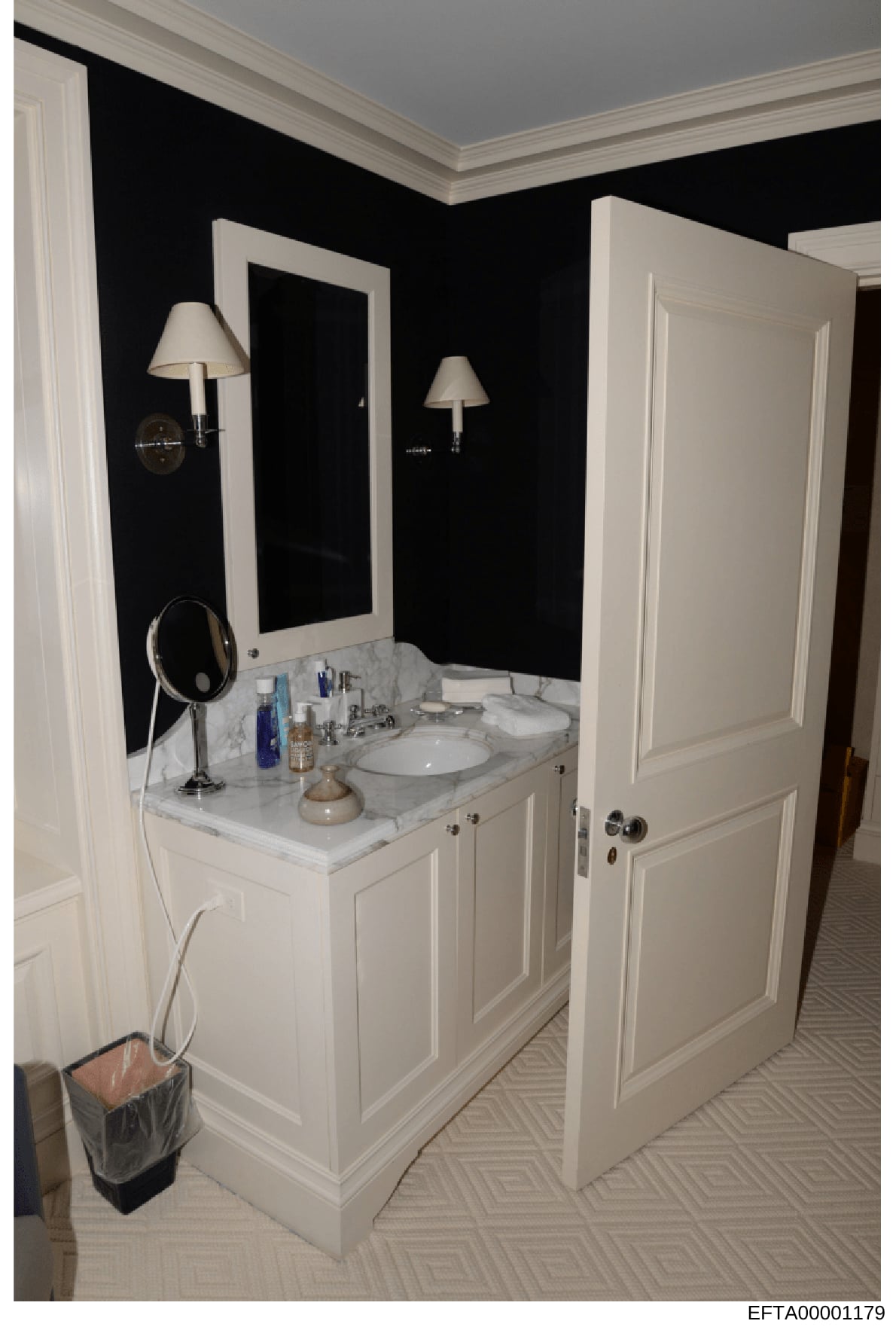 This is a photograph of a luxury bathroom interior, likely from one of Epstein's properties. The image shows a contemporary bathroom design with a white dual-sink marble vanity, black accent walls, white trim and molding, wall-mounted sconces, and mo