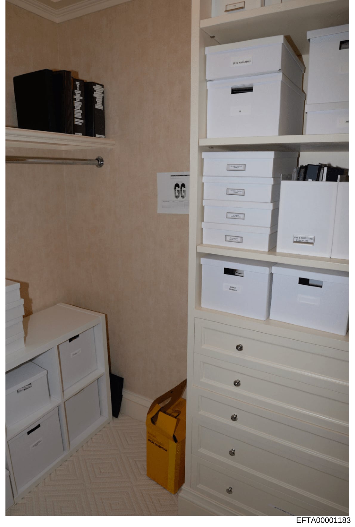 This is a photograph of a storage closet containing numerous white labeled boxes and filing containers arranged on shelves and in drawers. The boxes appear to be systematically organized and labeled, suggesting they contain archived or catalogued mat