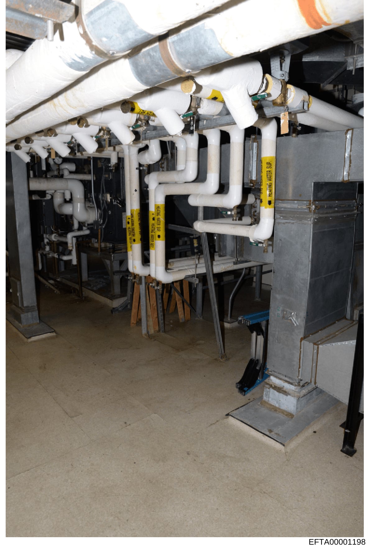 This is a photograph of a basement mechanical room showing HVAC and plumbing infrastructure with white PVC piping, ductwork, and various mechanical equipment. The image appears to be documentation of building systems at a property, likely taken durin