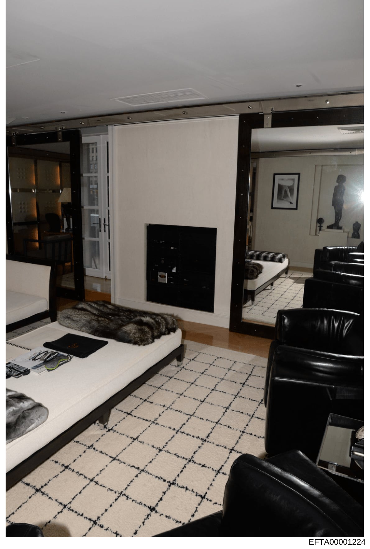 This is an evidence photograph showing the interior of a high-end residential space, featuring contemporary black and white décor with leather seating, marble flooring, and a fireplace. The image documents the property's design and layout as part of 