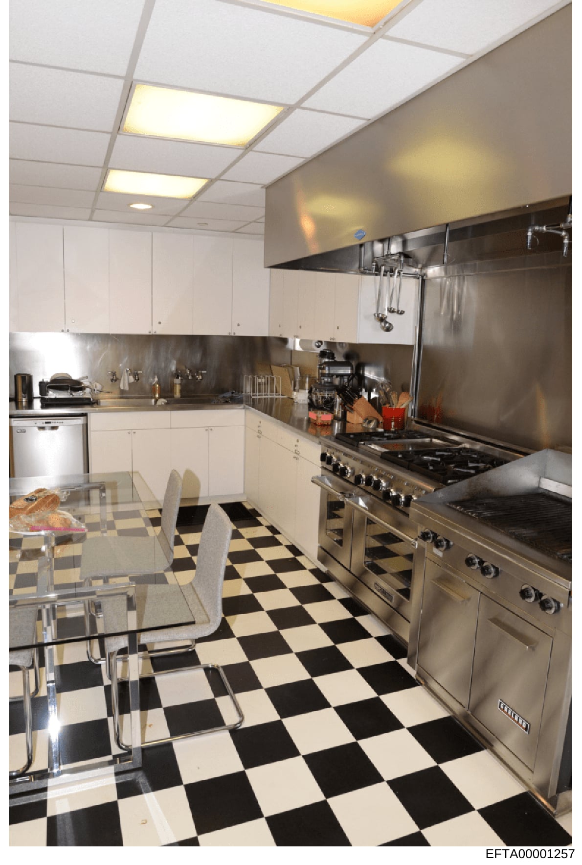 This is a photograph of a modern, professionally-equipped kitchen space featuring stainless steel commercial-grade appliances, white cabinetry, and distinctive black-and-white checkered flooring. The kitchen appears to be part of a high-end residence