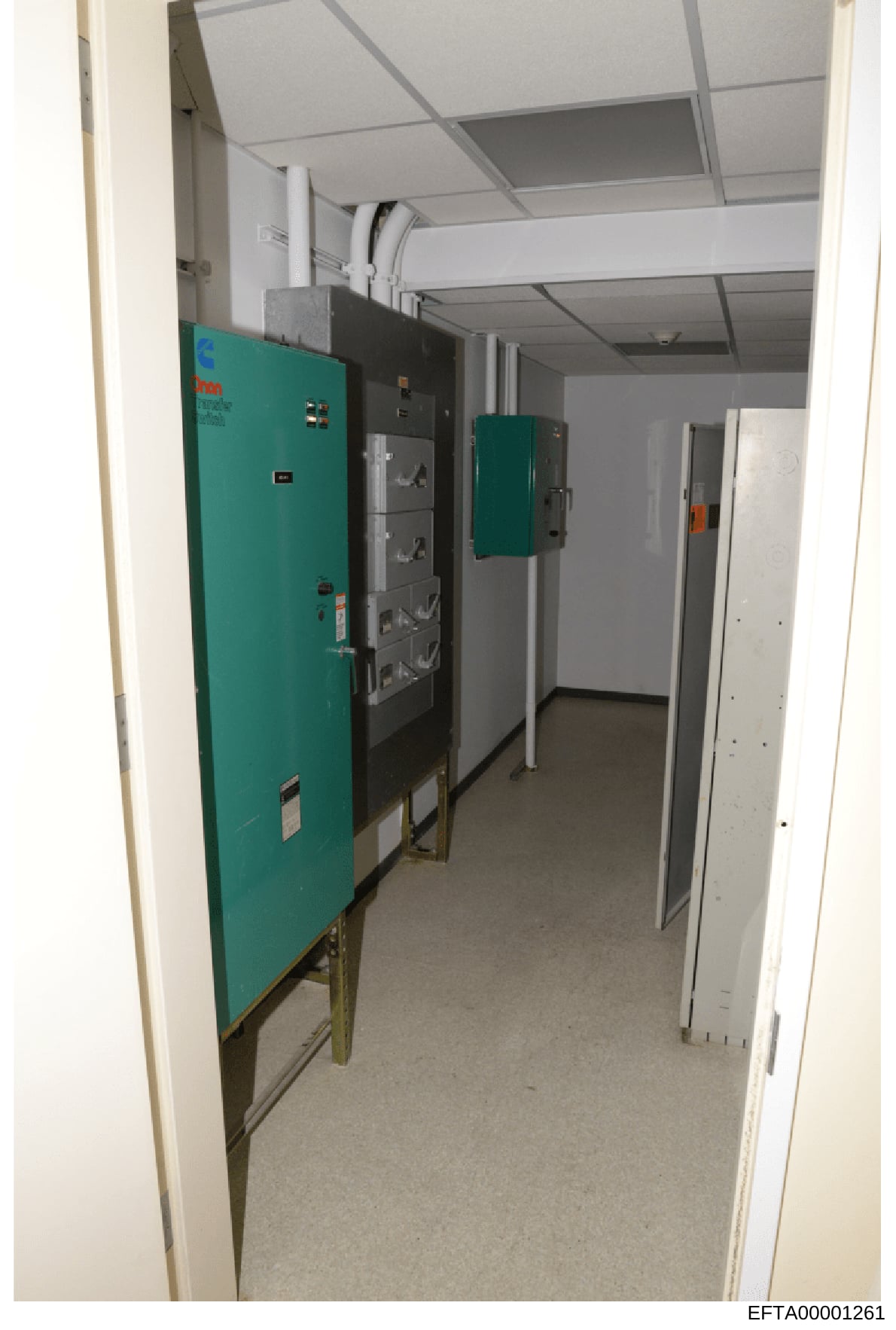 This photograph shows an interior utility room containing electrical infrastructure, including turquoise-colored power distribution panels, electrical boxes, and related equipment. The image appears to be documentation of building systems, possibly t