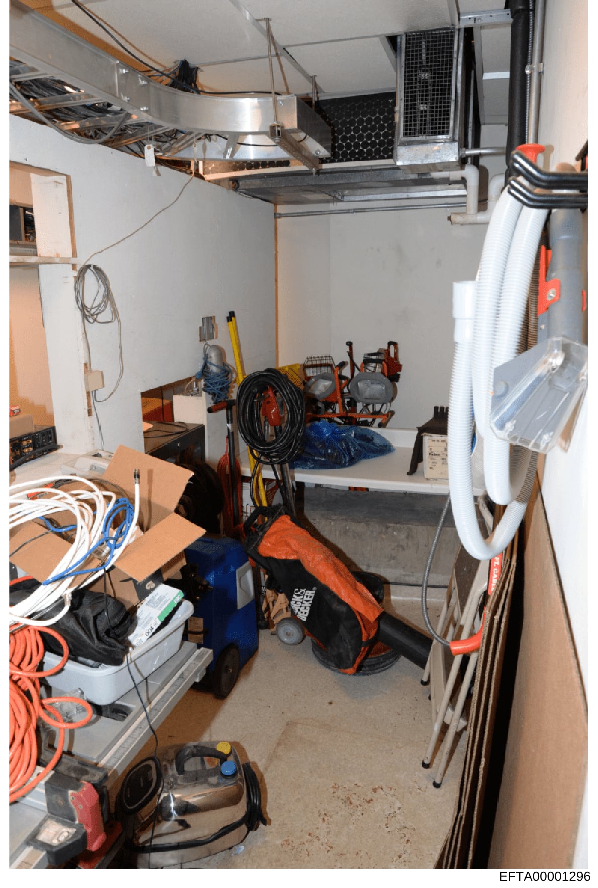 This photograph shows an organized storage space or garage containing various household and maintenance tools and equipment. The room has shelving units mounted on the walls and ceiling, storing items including power tools, extension cords, cleaning 