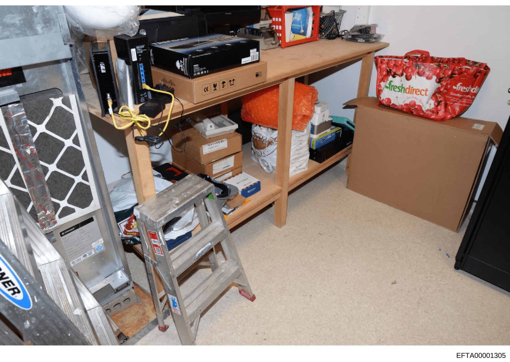 This is an evidence photograph showing the interior of a storage room or garage space containing various household items, electronics, and supplies. The image documents the physical contents and layout of what appears to be a residential storage area