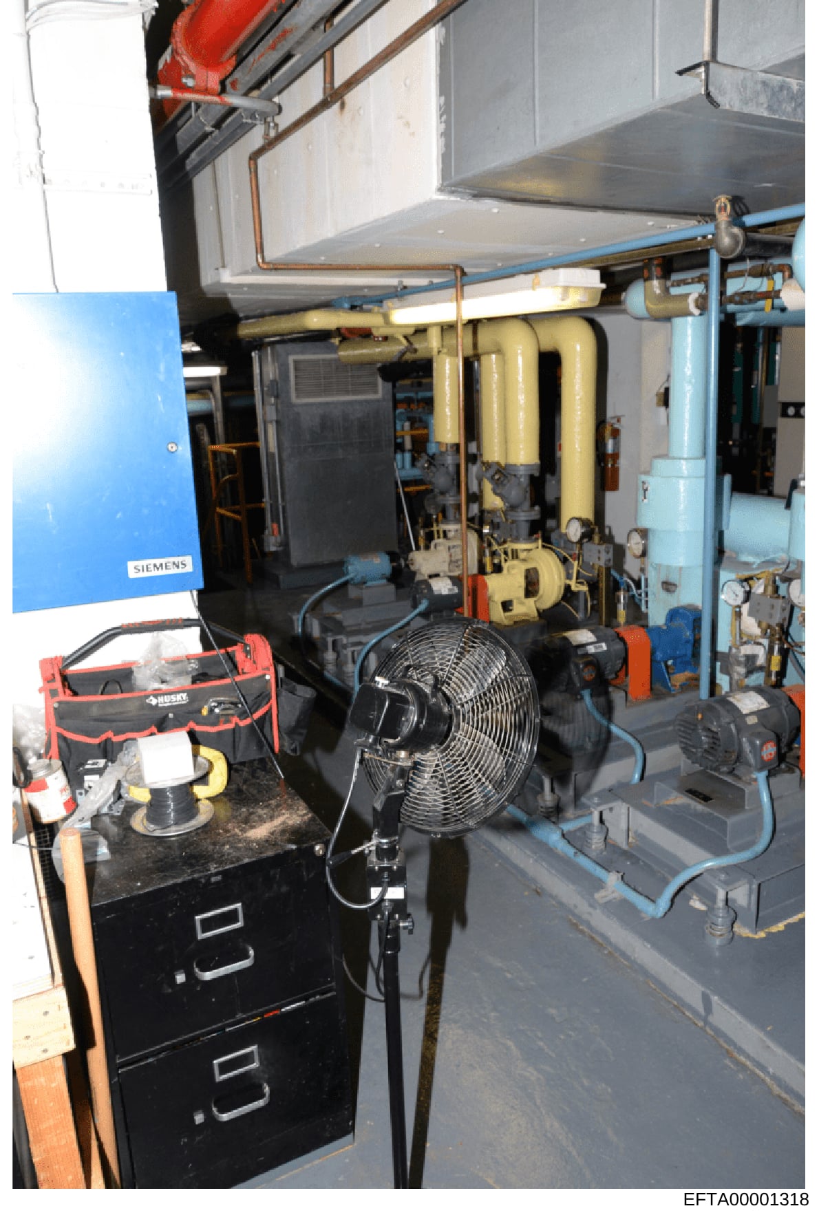 This is an evidence photograph showing the interior of a mechanical equipment room or basement utility area containing industrial HVAC, plumbing, and electrical systems. The image documents building infrastructure including a Siemens boiler unit, wat