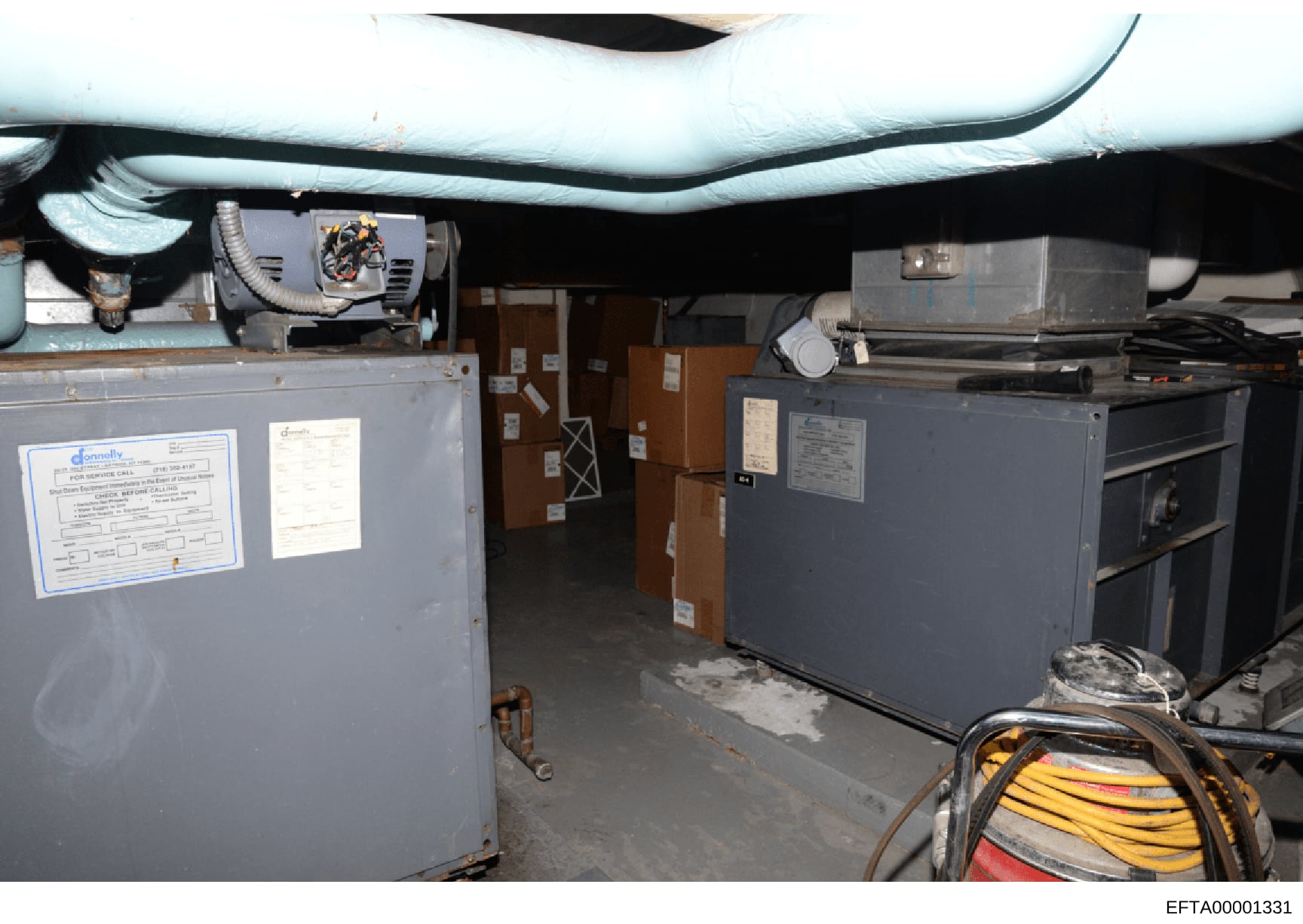 This is a photograph of a basement or mechanical room showing industrial HVAC equipment, electrical systems, and utility infrastructure. The image documents the mechanical systems in what appears to be a residential or commercial property, with visib