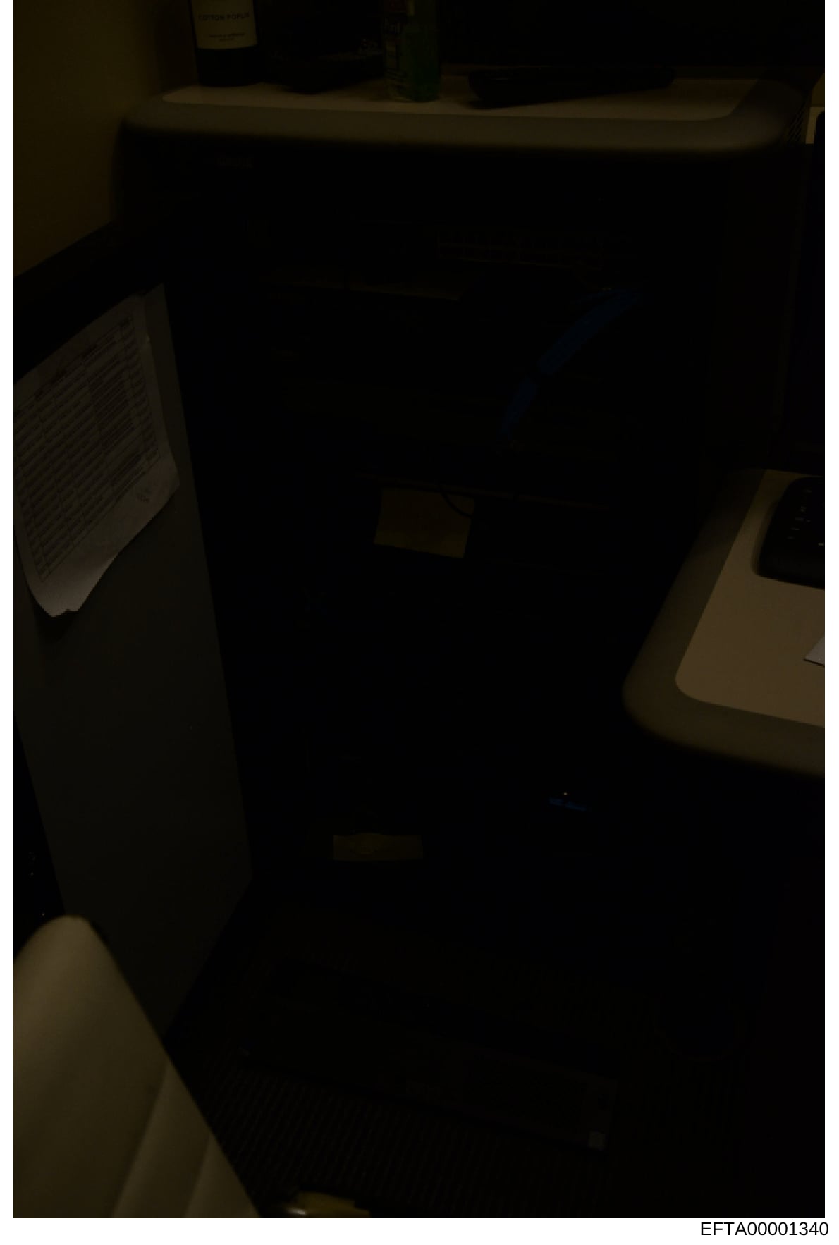 This is a poorly lit photograph of an interior room, likely taken during an evidence-gathering investigation. The image shows minimal detail due to low lighting conditions, with only shadowy outlines of furniture and fixtures visible. The photograph