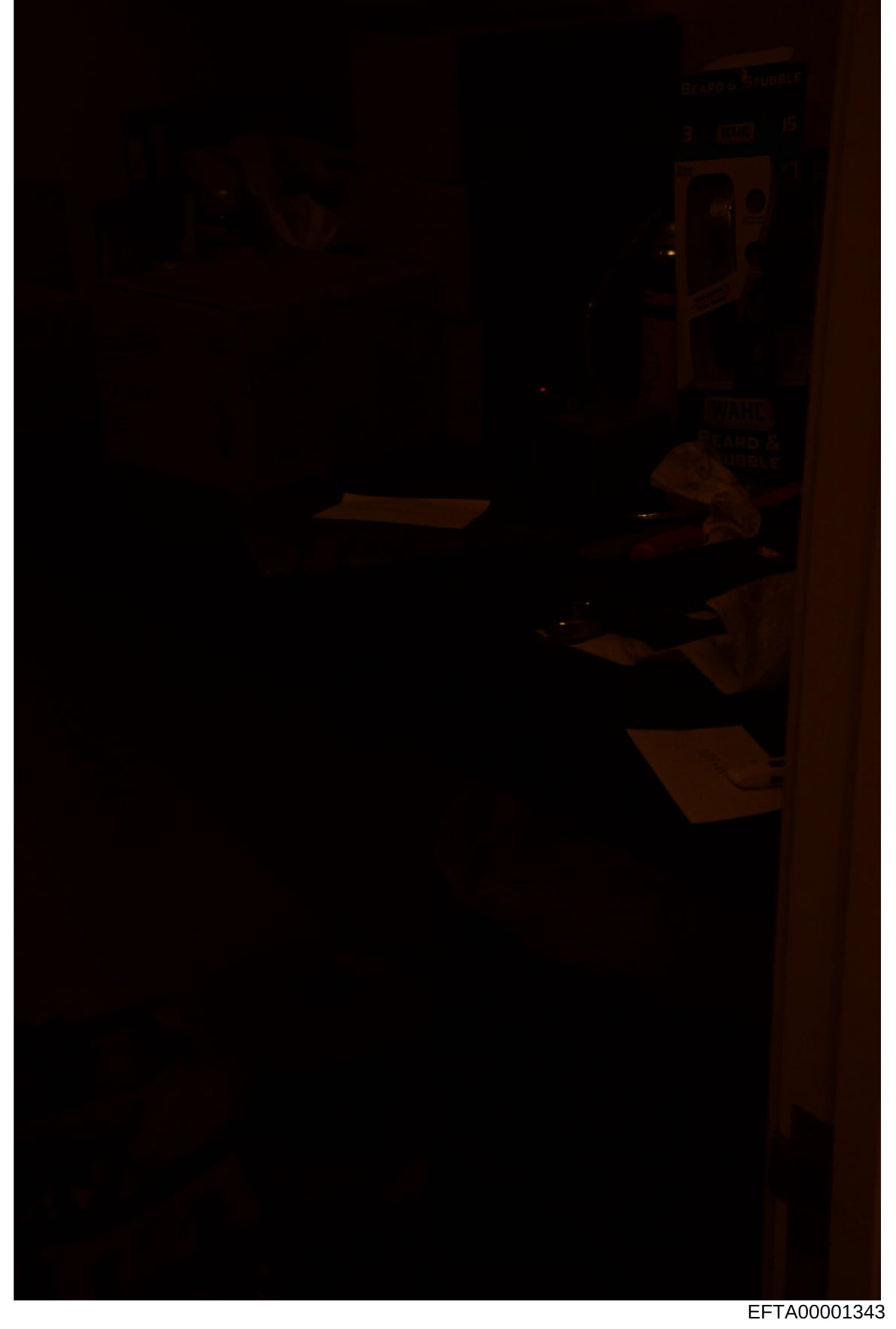 This is a poorly lit photograph of an interior room, likely from a property associated with the investigation. The image is extremely dark with minimal visibility, showing what appears to be wooden furniture or fixtures. The quality and darkness make