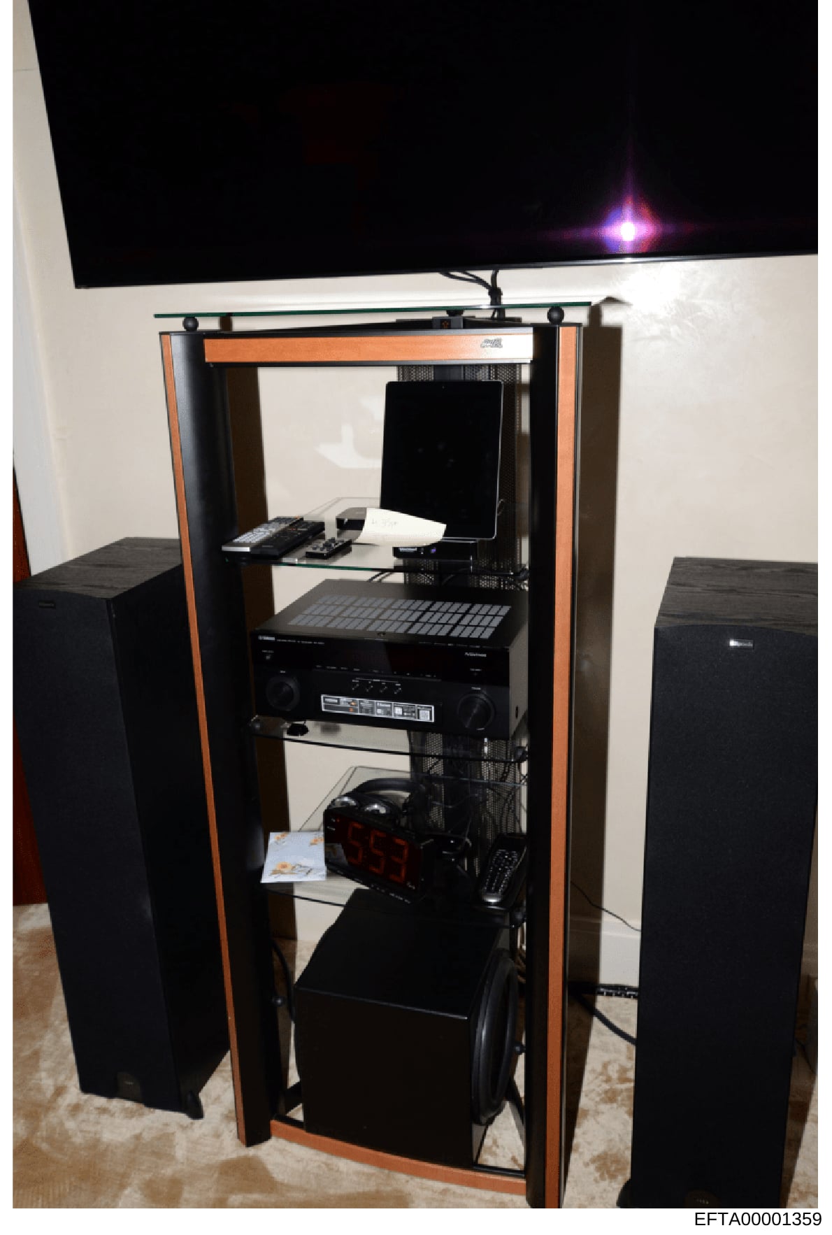This is a photograph of a modern computer workstation setup featuring a tall tower-style cabinet with orange and black frame housing multiple electronic components. The setup includes a wall-mounted flat-screen monitor, keyboard, mouse, audio equipme