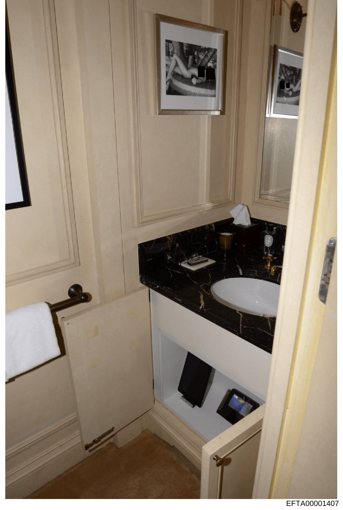 This is a photograph of a luxurious bathroom interior, showing a modern vanity with black marble countertop, white circular sink, framed black-and-white artwork on cream-colored walls, and brass fixtures. The image appears to be evidence documentatio