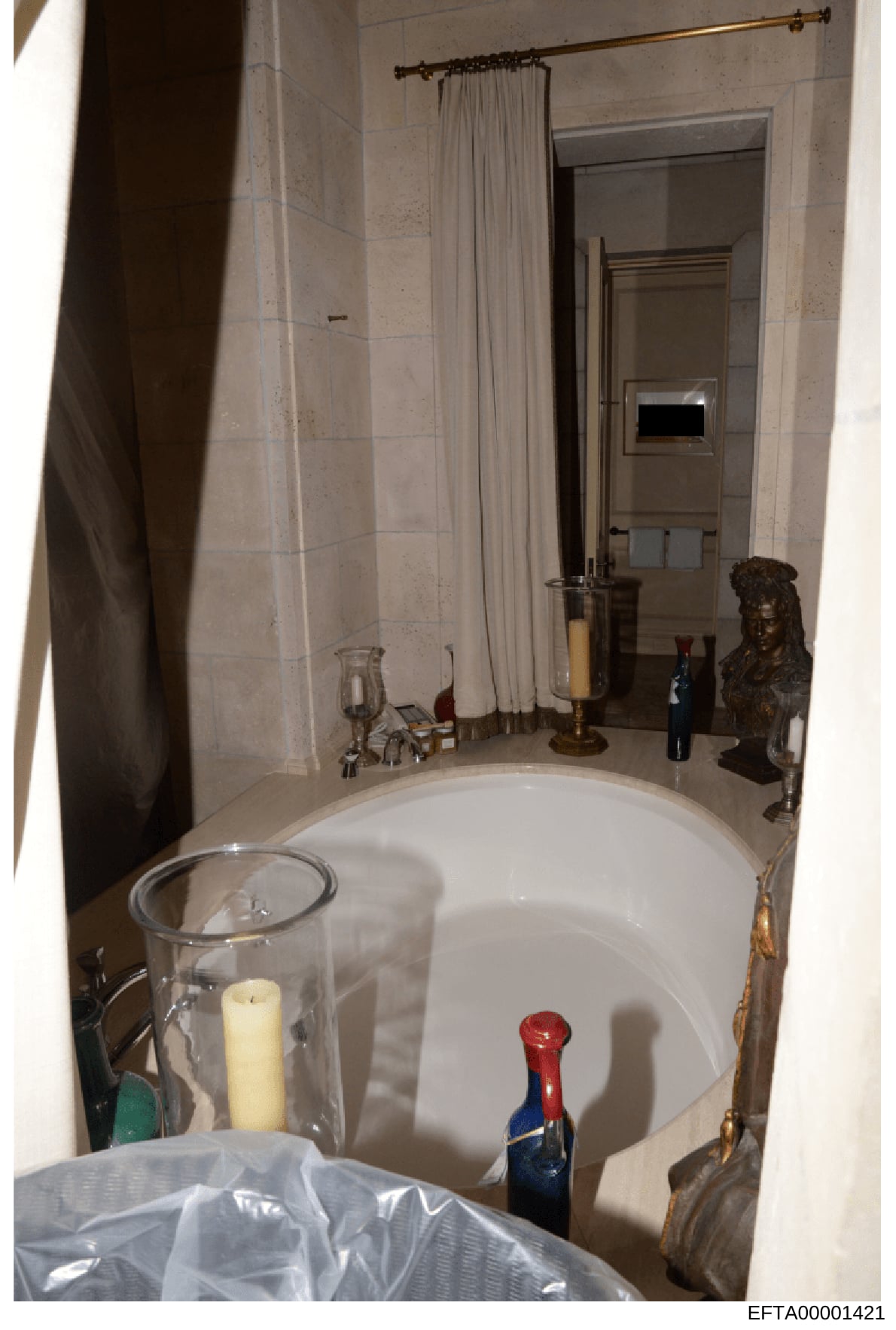 This is a photograph of an upscale bathroom interior, likely from one of Jeffrey Epstein's residences. The image shows a large soaking tub, marble walls, decorative elements including a bronze bust sculpture, candleholders, and luxury bathroom fixtur