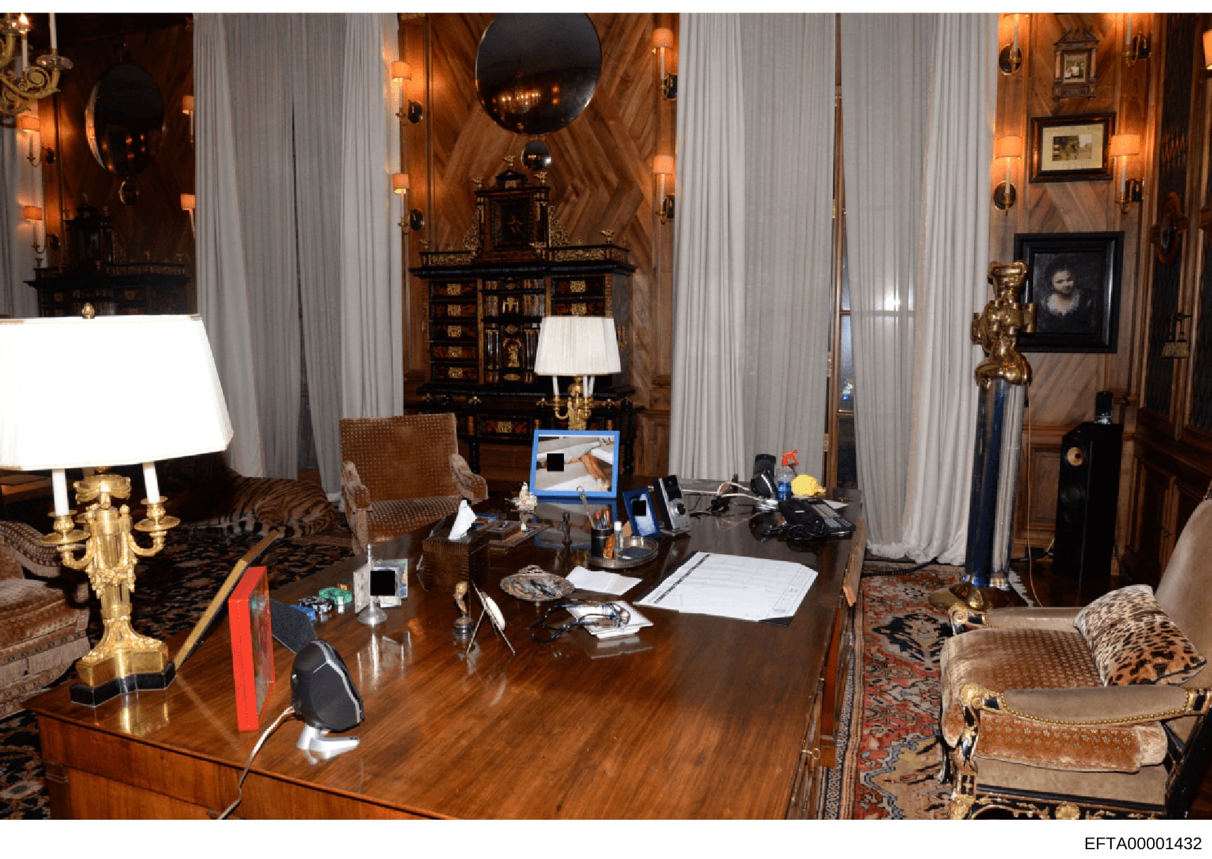 This photograph shows a formally decorated office or study room within a high-end residence, featuring expensive furnishings, artwork, and decor. The room contains a working desk with computer equipment, personal items, and documents, suggesting it s