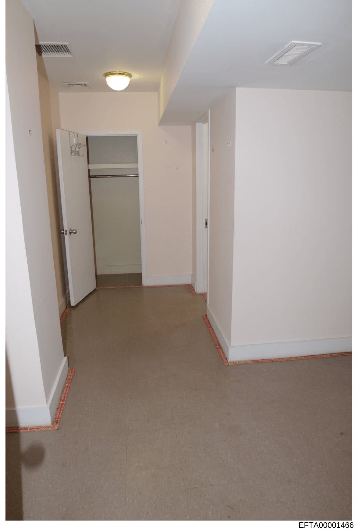 This is a photograph of an interior hallway with white walls, recessed lighting, and an open closet door revealing shelving. The hallway appears to be part of a residential property under investigation, with red tape marking visible on the floor bord