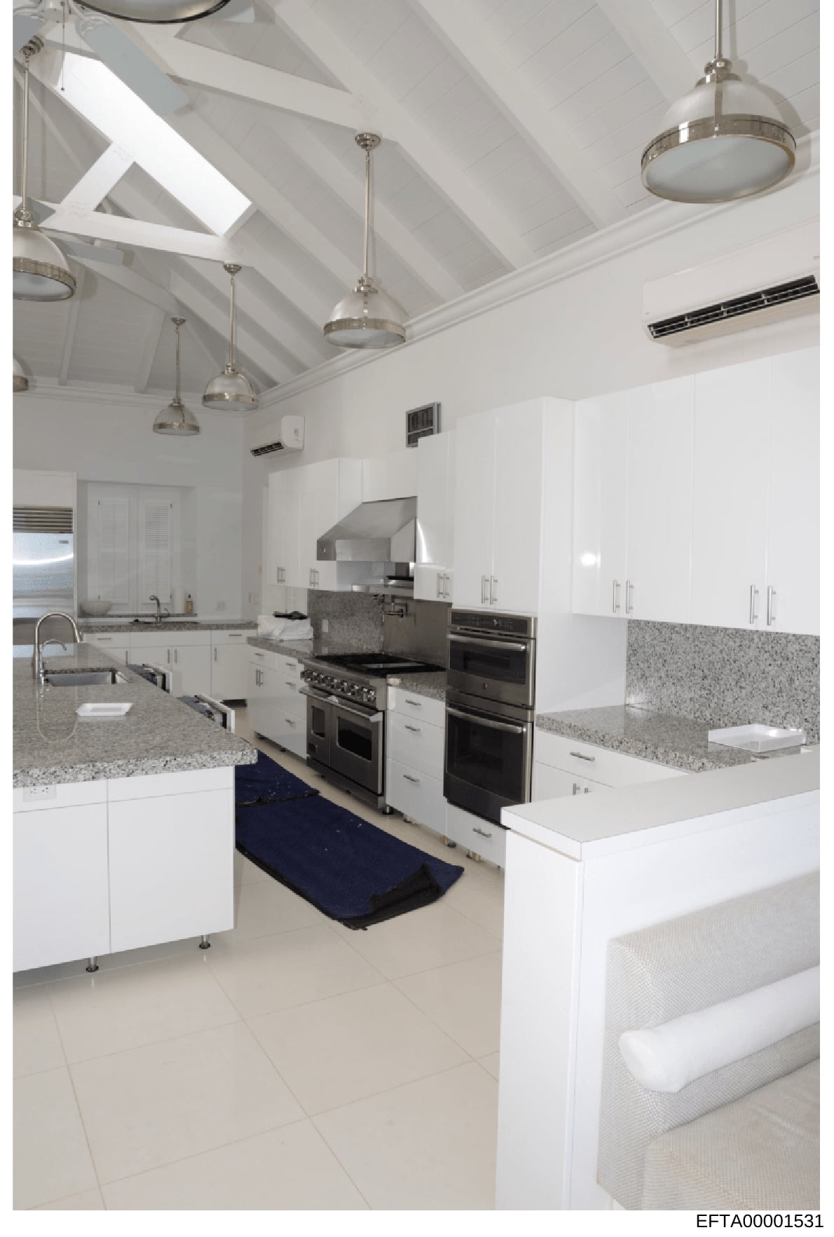 This is a photograph of a contemporary kitchen space, likely from one of Jeffrey Epstein's properties. The image shows a recently renovated or upscale kitchen featuring white cabinetry, granite countertops, stainless steel professional-grade applianc
