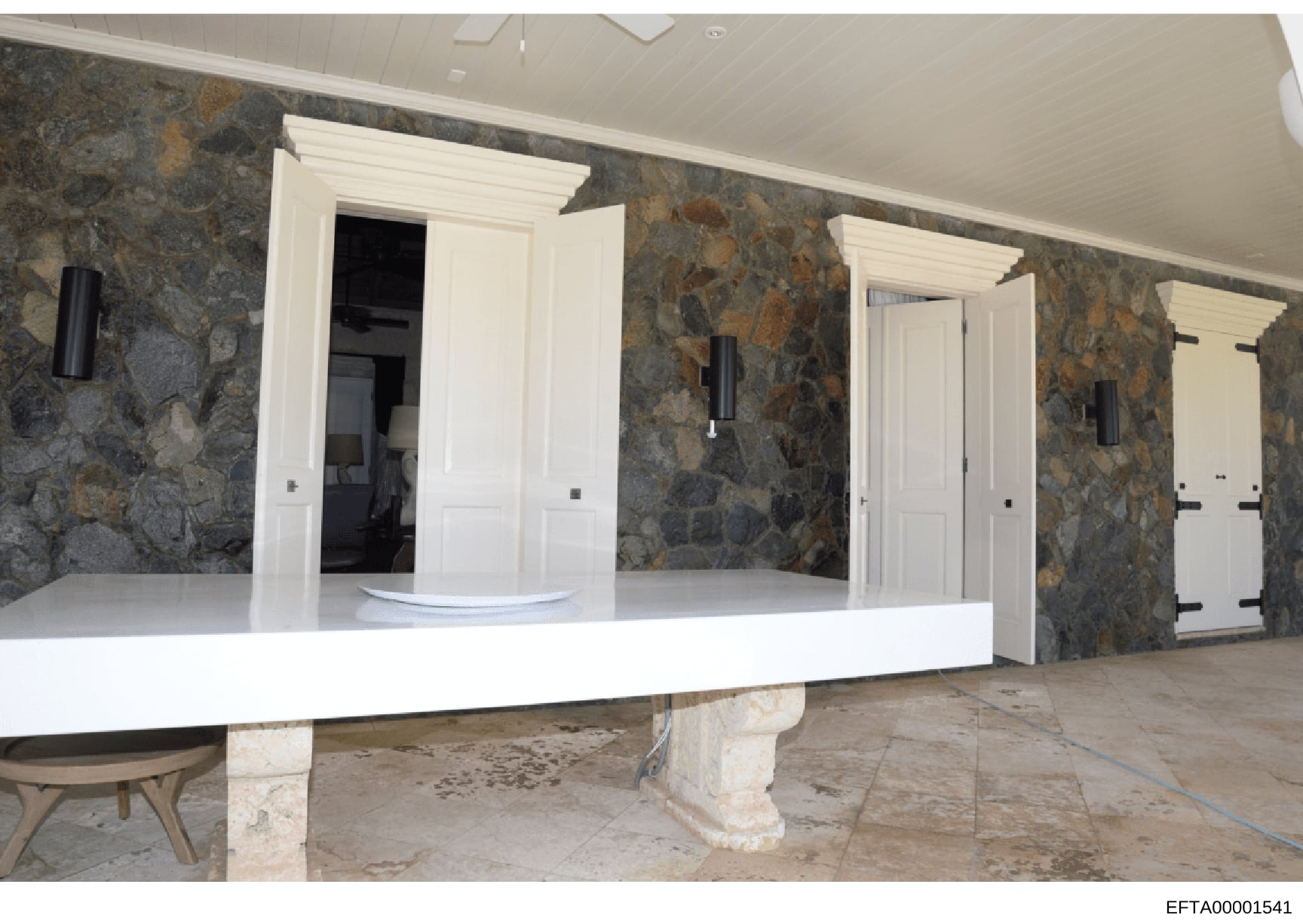 This photograph shows an interior room or hallway of a high-end residential property during renovation or construction phase. The space features distinctive slate or stone accent walls in gray and brown tones, white trim and doorframes, a white curve