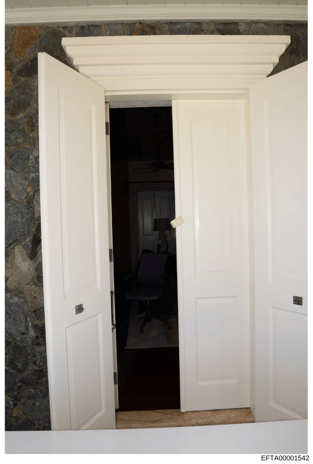 This is an evidence photograph showing an interior room with white double doors opening into a darkened space containing office furniture, including a black office chair. The photo documents the architectural features and interior layout of what appe