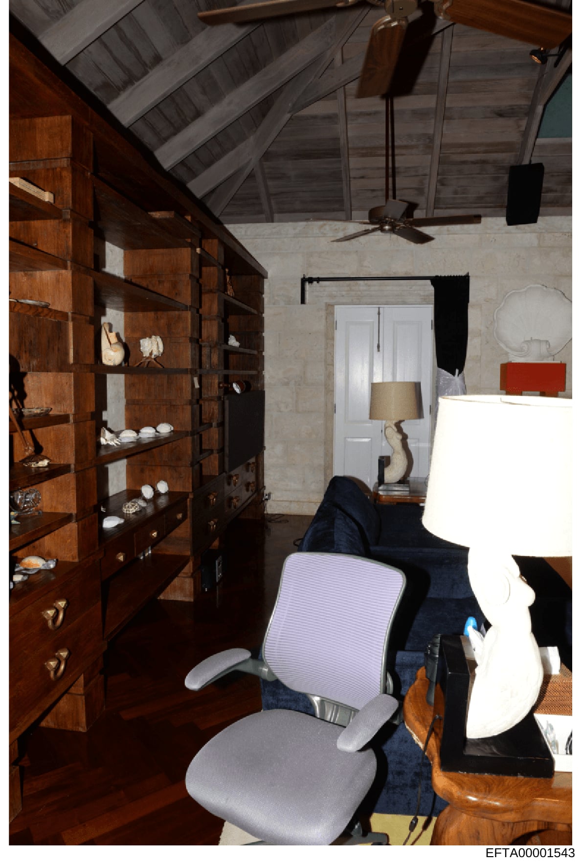 This is a photograph of an interior room space, likely an attic or upper floor area of a property, showing architectural details and furnishings. The room features vaulted ceilings with exposed beam work, built-in wooden shelving units displaying dec