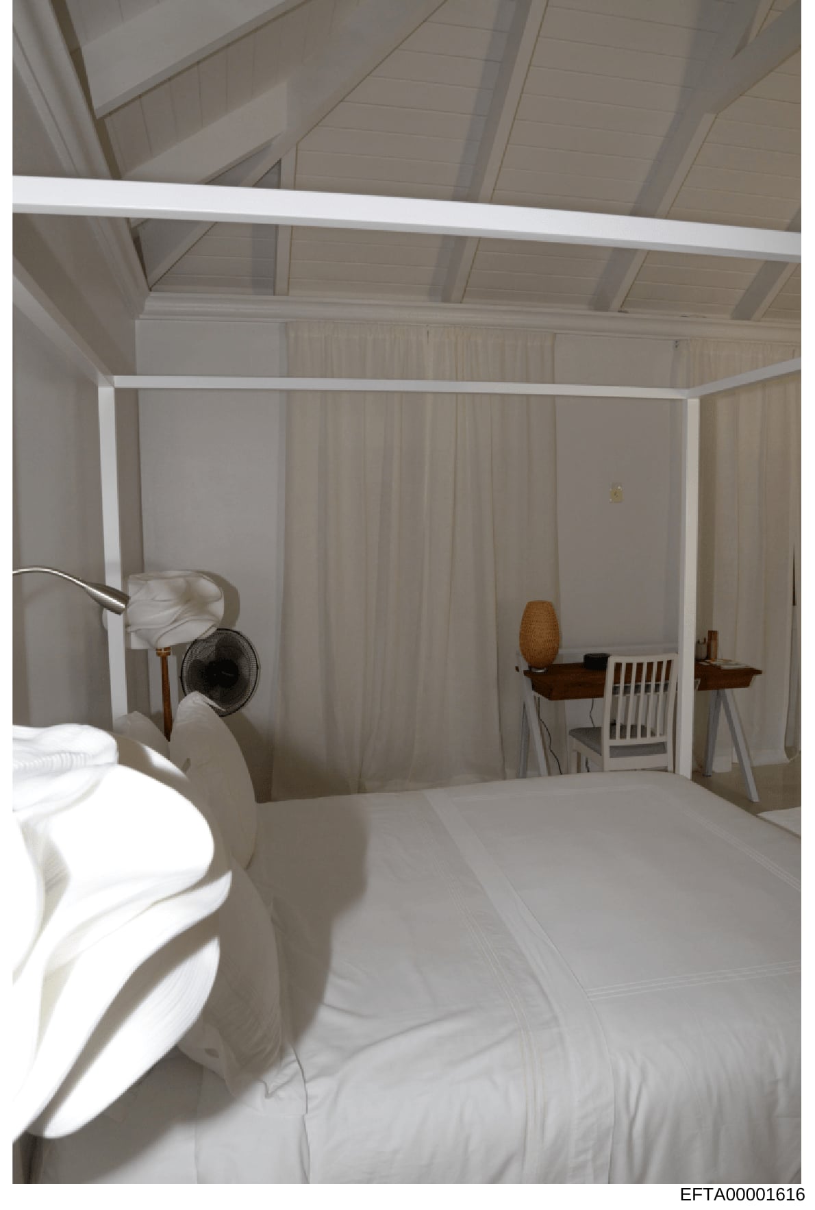 This is a photograph of a bedroom interior featuring a white four-poster canopy bed with sheer curtains, wooden furniture, and clean minimalist décor. The image appears to be evidence documentation from a property investigation, showing the bedroom's