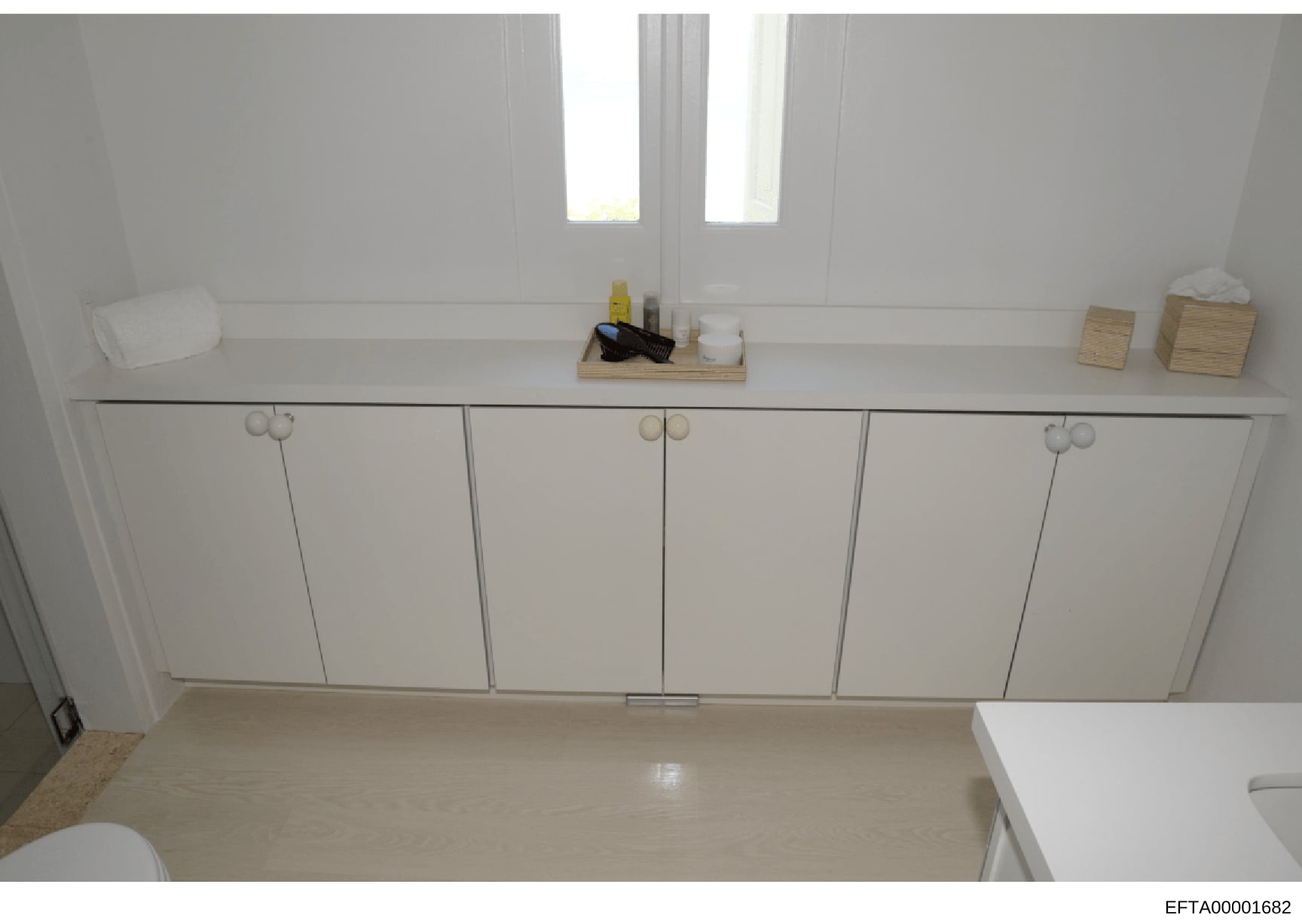 This is an overhead photograph of a bathroom interior showing a white vanity with six cabinet doors, countertop surfaces, and bathroom accessories. The image documents the physical space and layout of what appears to be a property under investigation