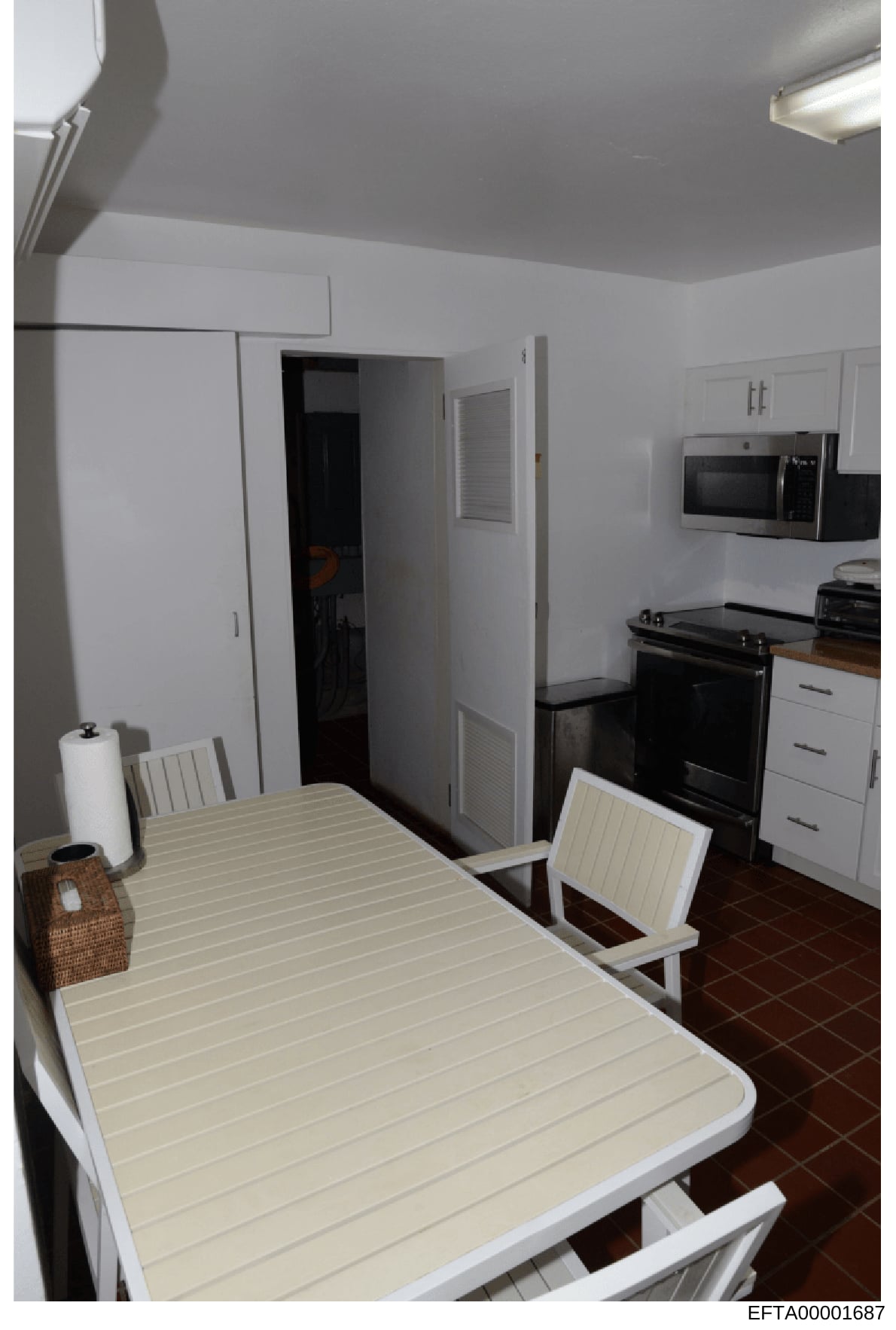 This is a photograph of a residential kitchen and dining area, showing modern appliances, cabinetry, and a dining table with chairs. The image appears to be documentation of property interiors, likely taken during an investigation or evidence collect
